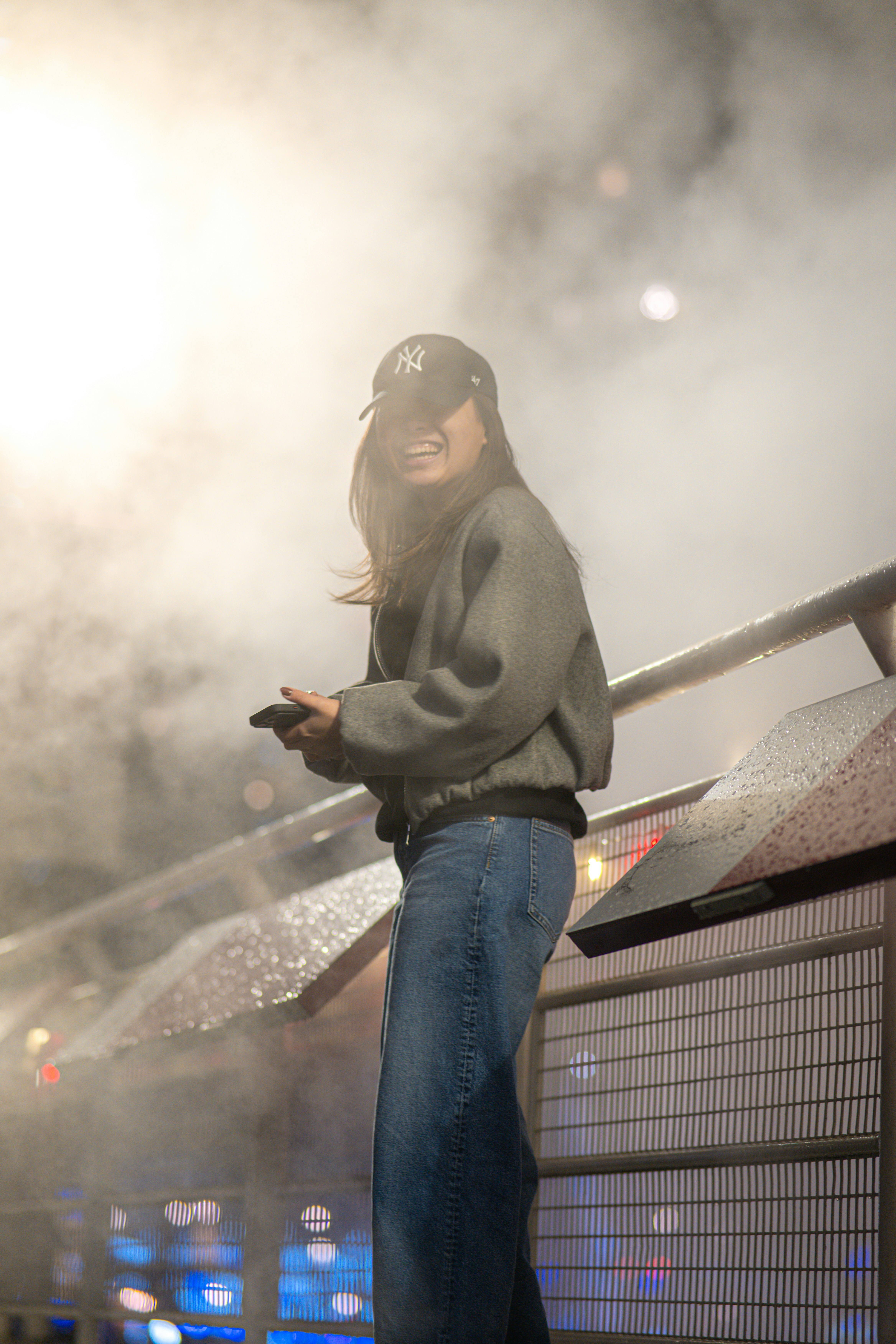 A woman in a baseball cap holds a phone