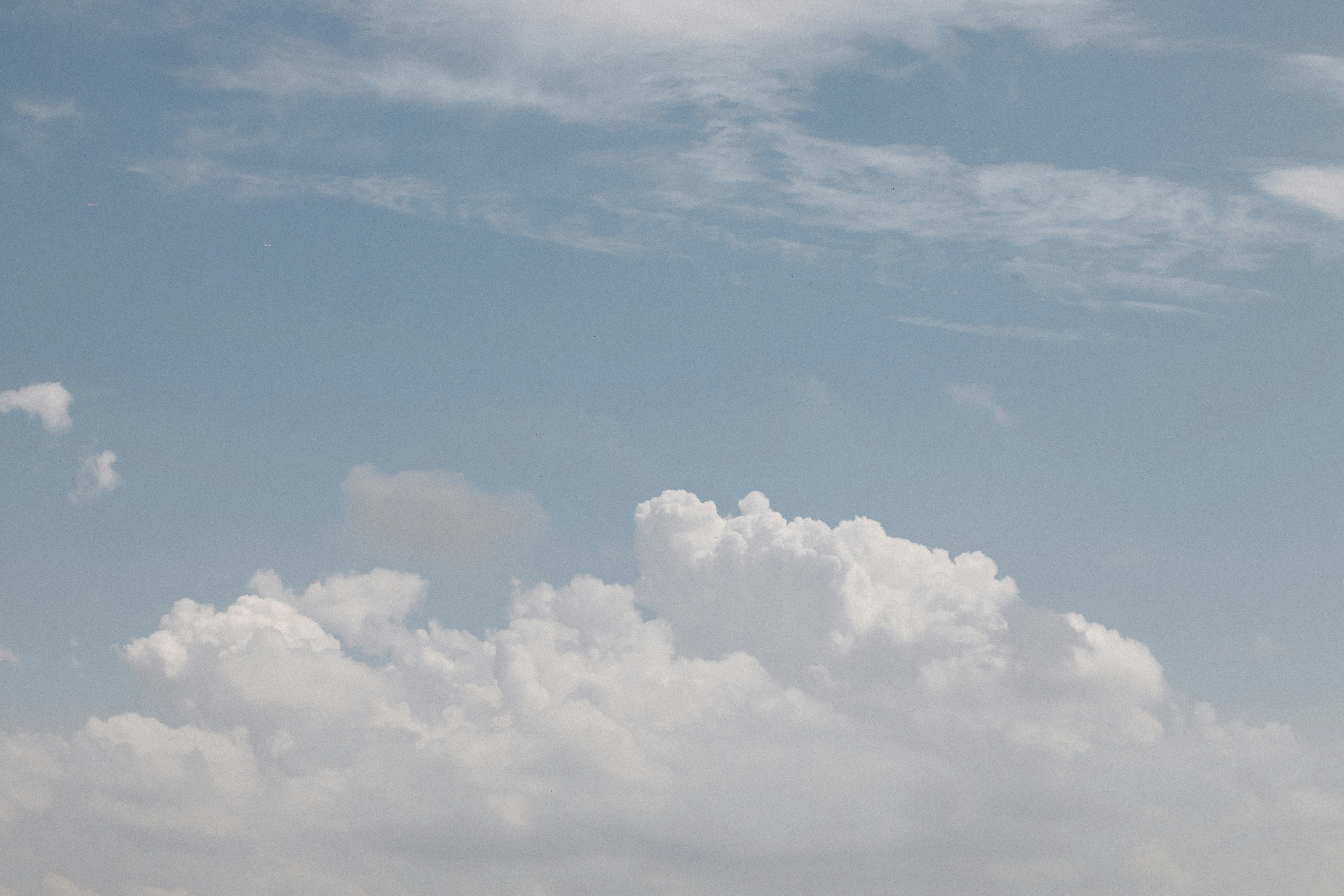Fluffy white clouds against a pale blue sky