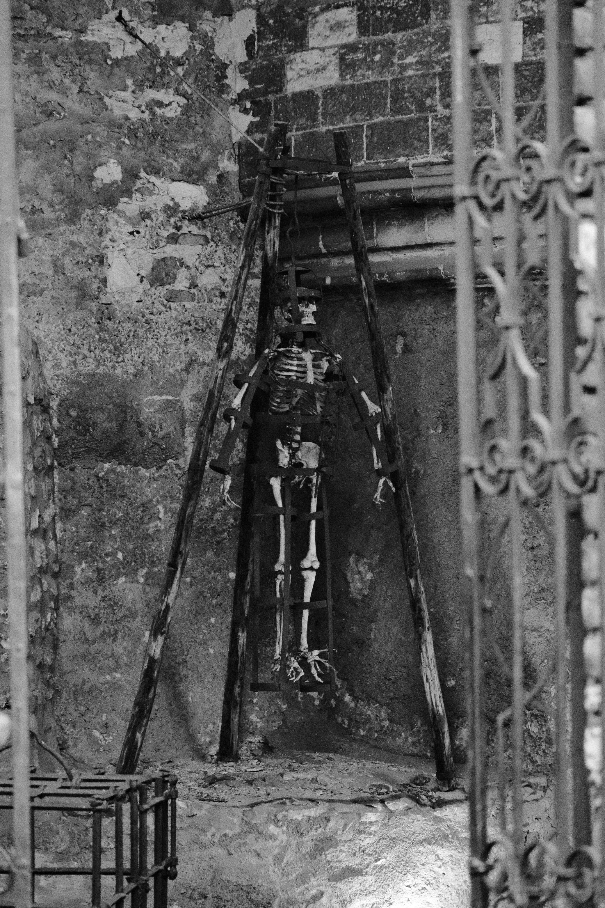 石の部屋の木製のラックに吊るされた骸骨