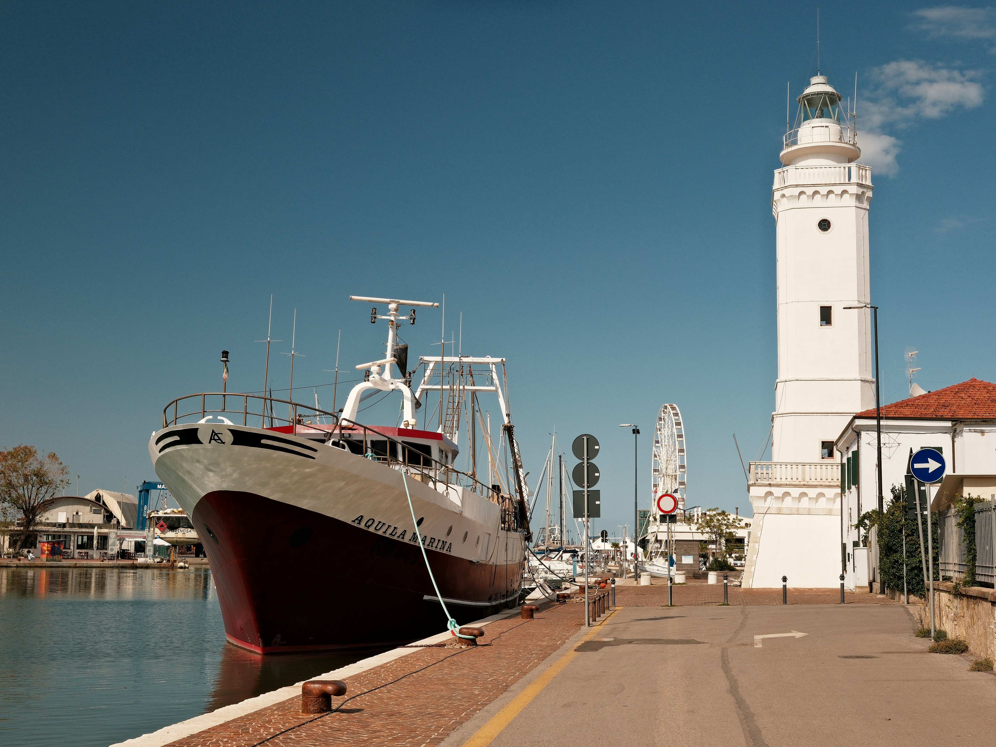 Una grande nave attraccata accanto a un faro bianco.