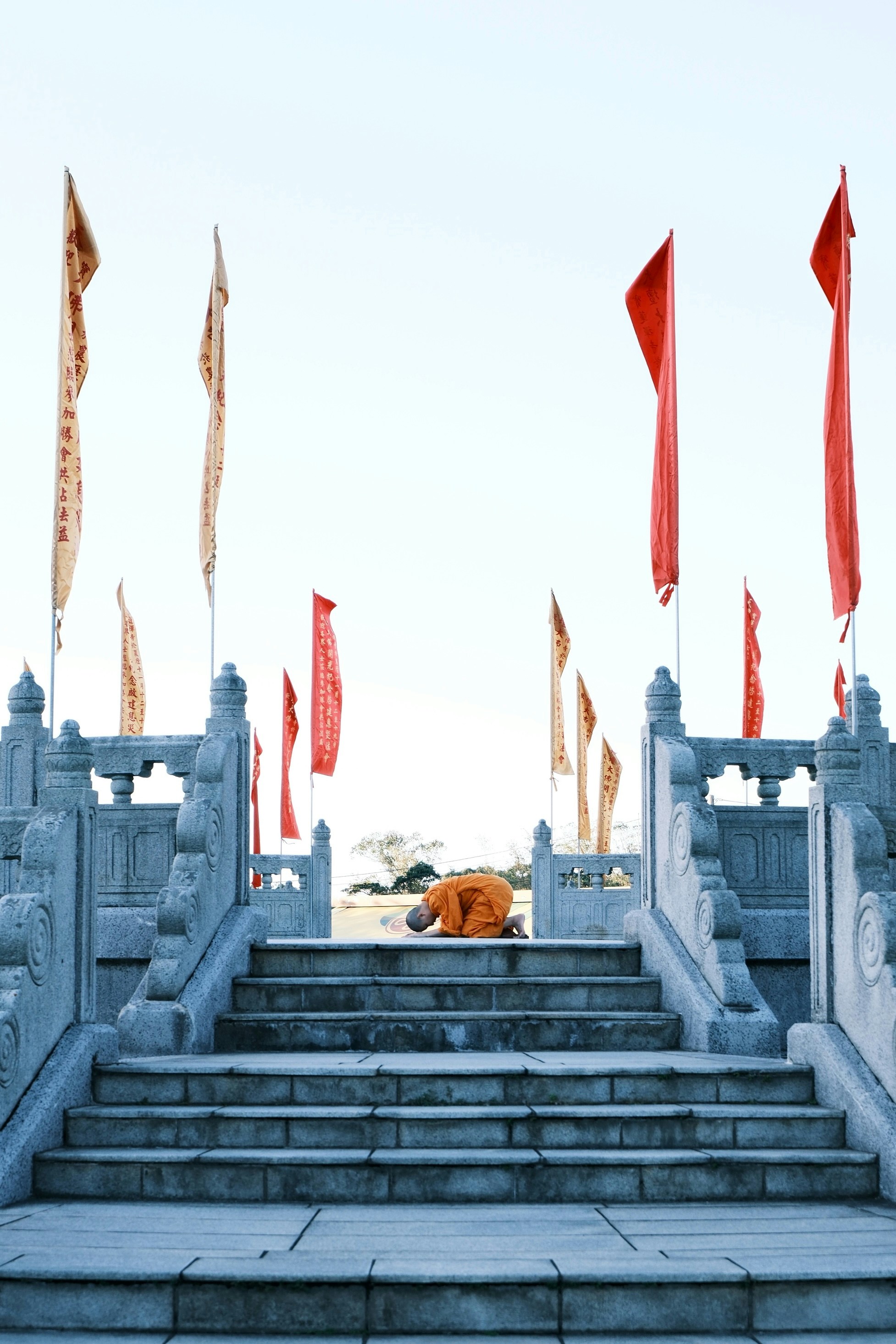 Monk prostrating on steps with prayer flags