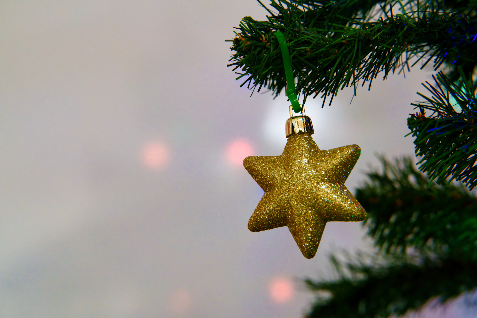 A golden star ornament hangs on a christmas tree
