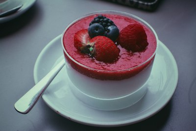 Panna cotta crémeuse nappée de coulis de fruits rouges fraises et framboises