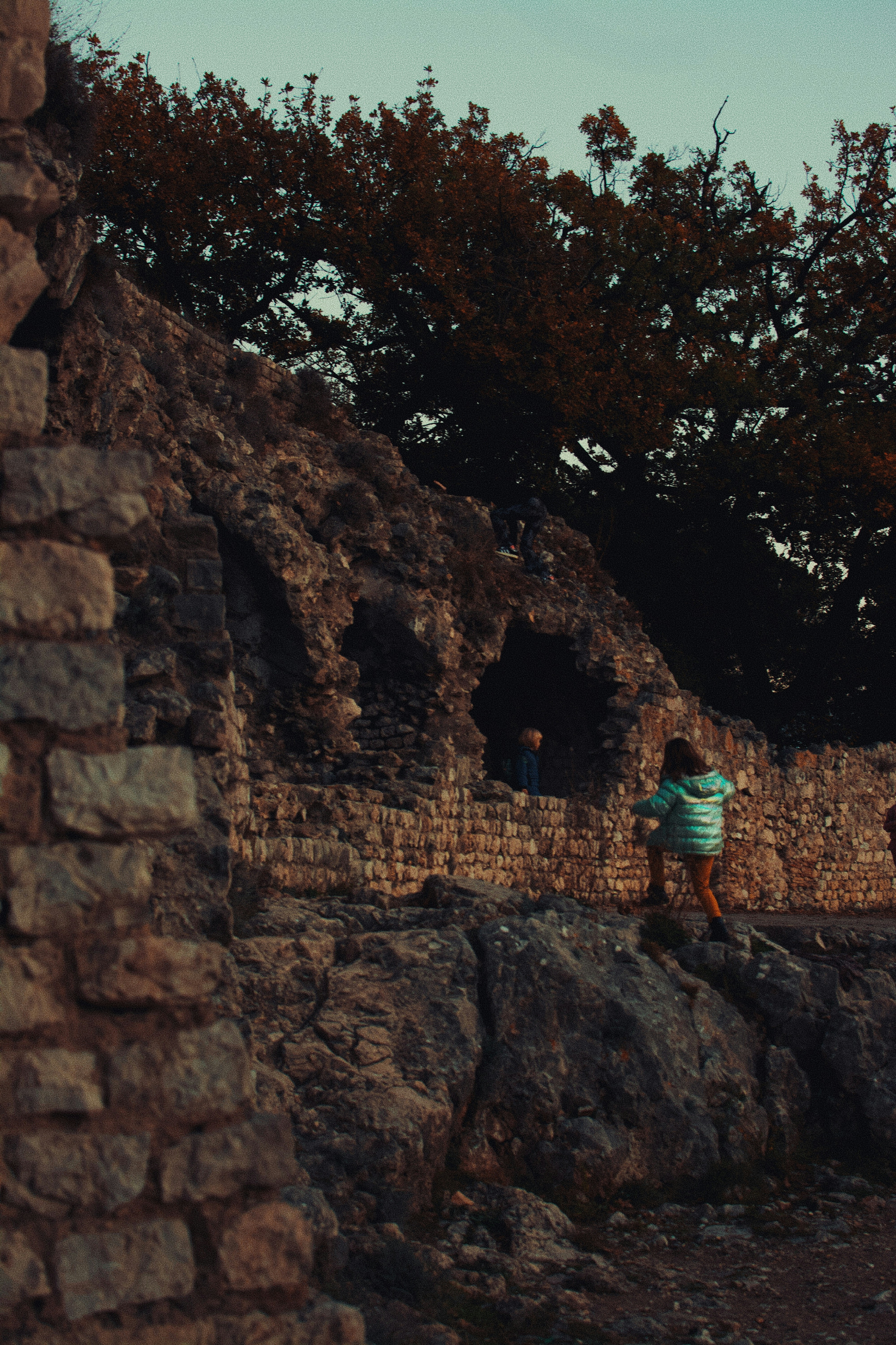 Child climbing on ancient stone ruins with trees.