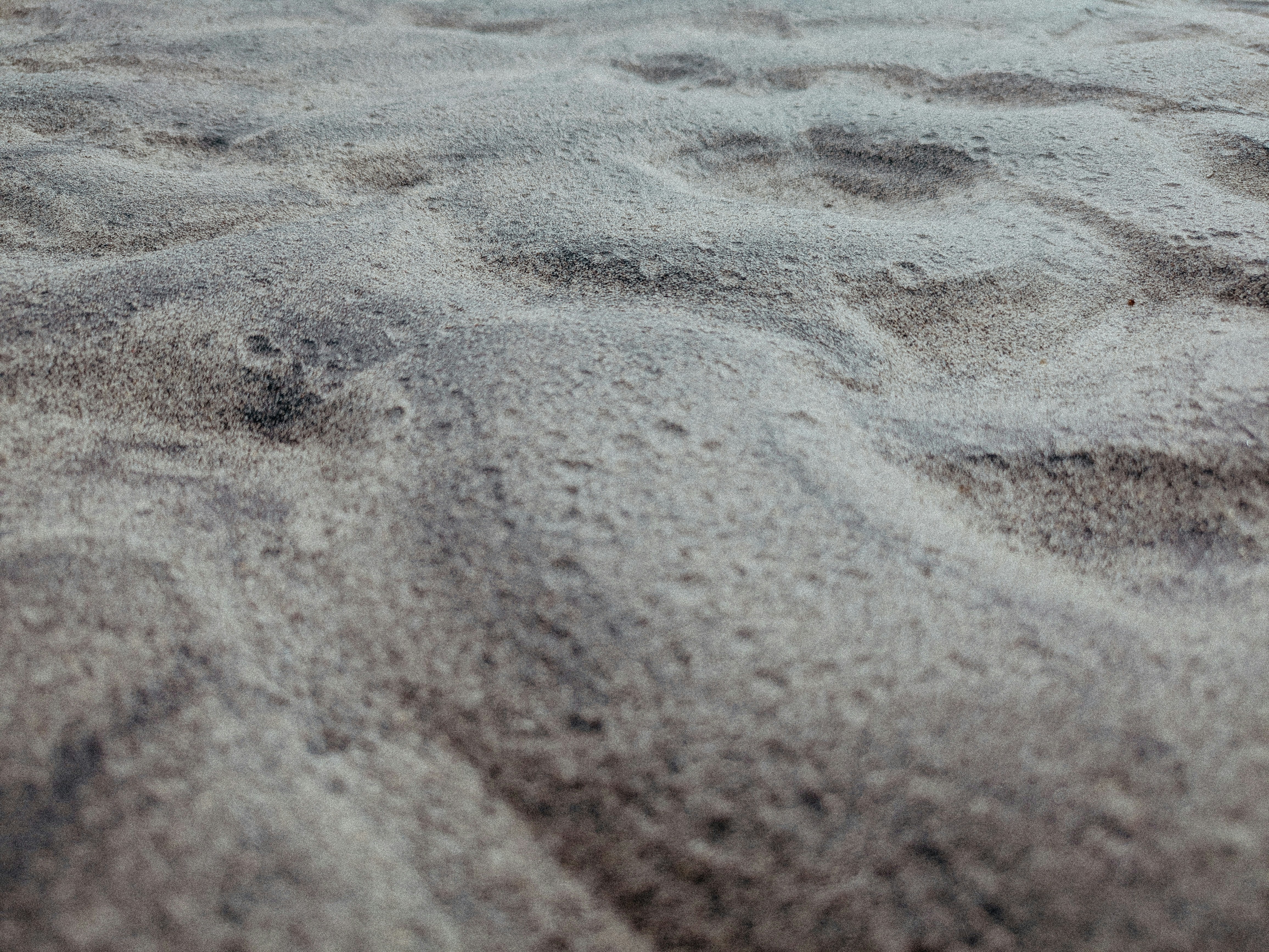 Grey, wavy, bumpy sand, which is pitted in places. There are varying valleys and troughs in the surface.