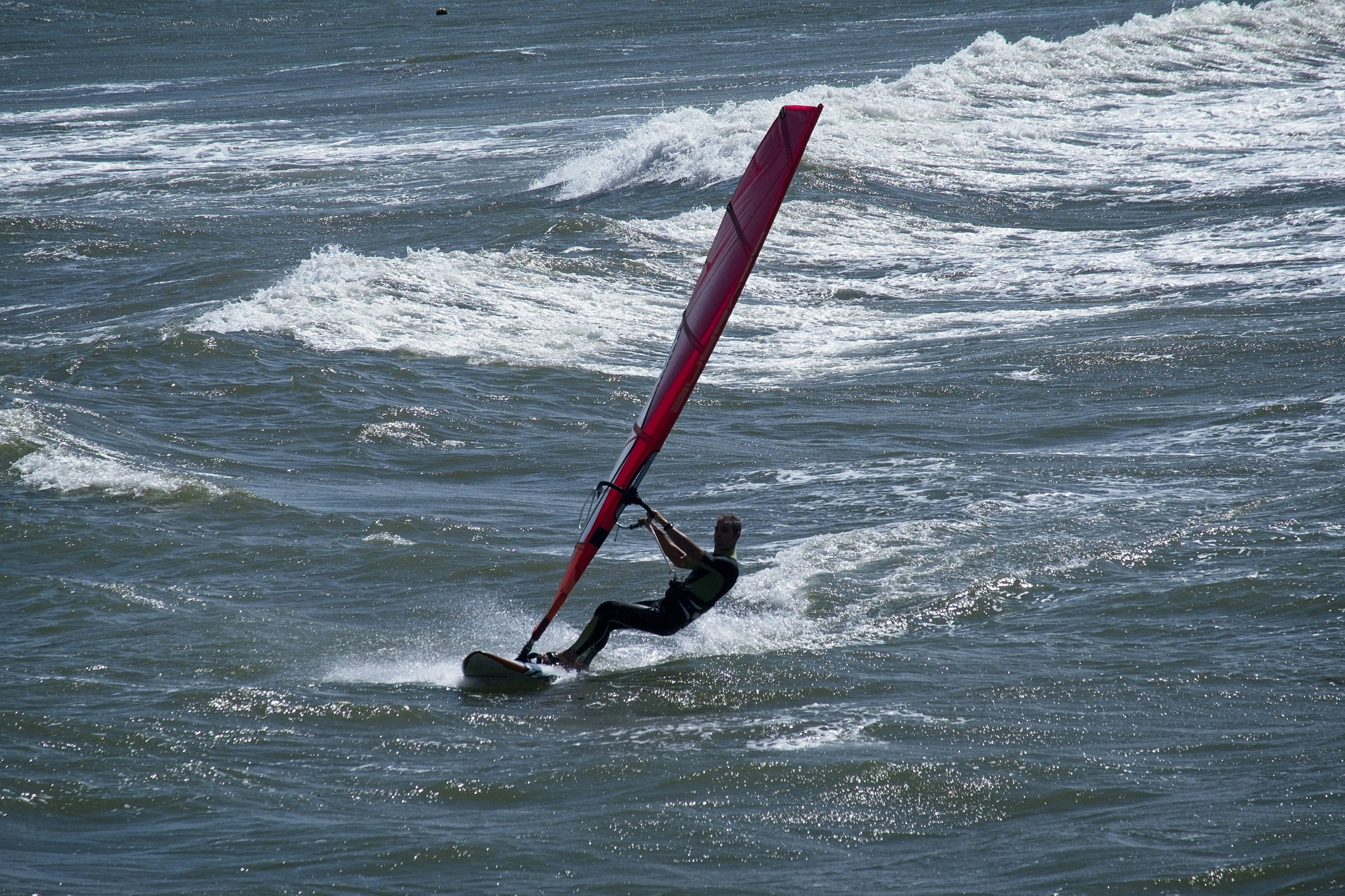 A person windsurfing on choppy blue water