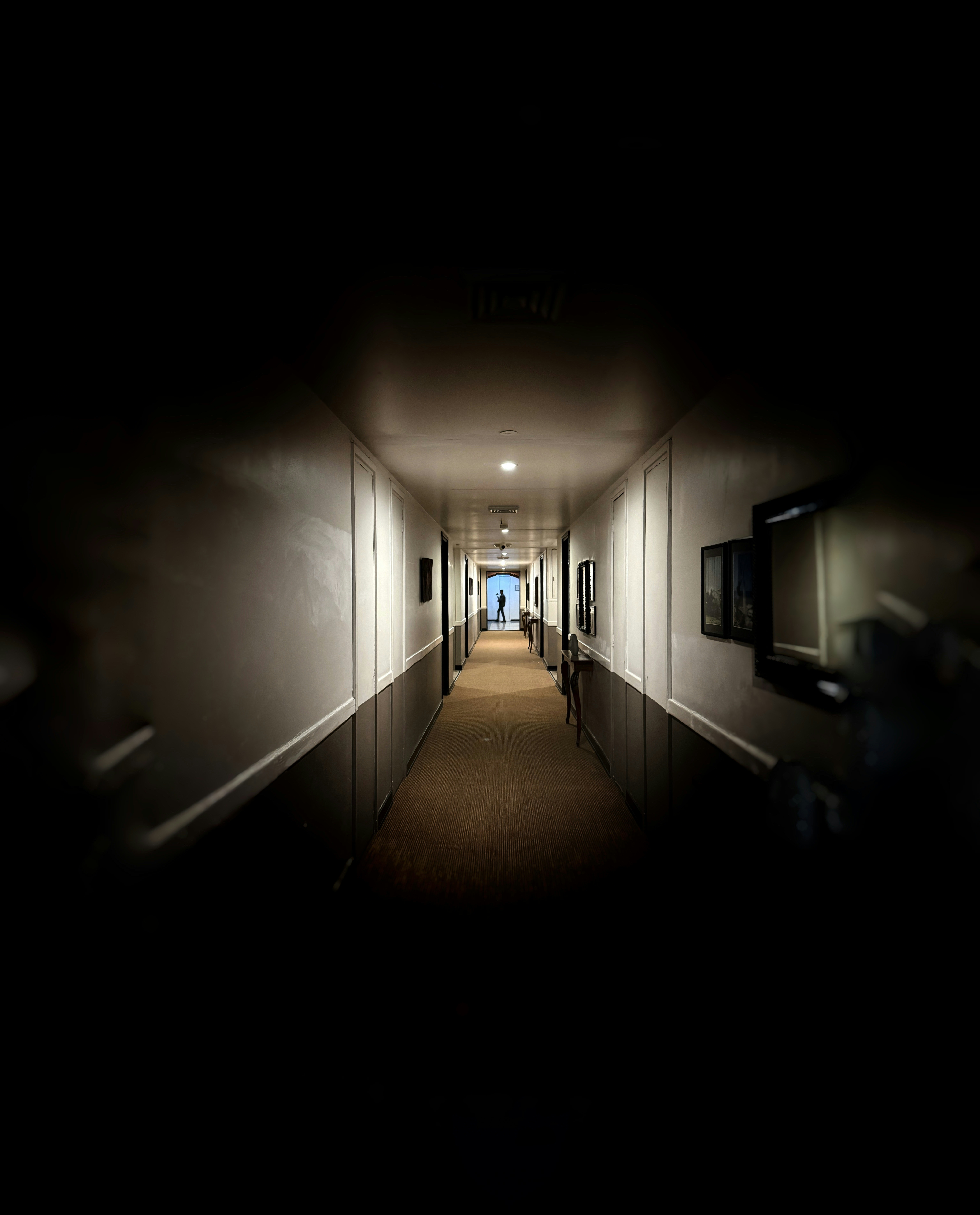 A dark hallway with a figure at the end.