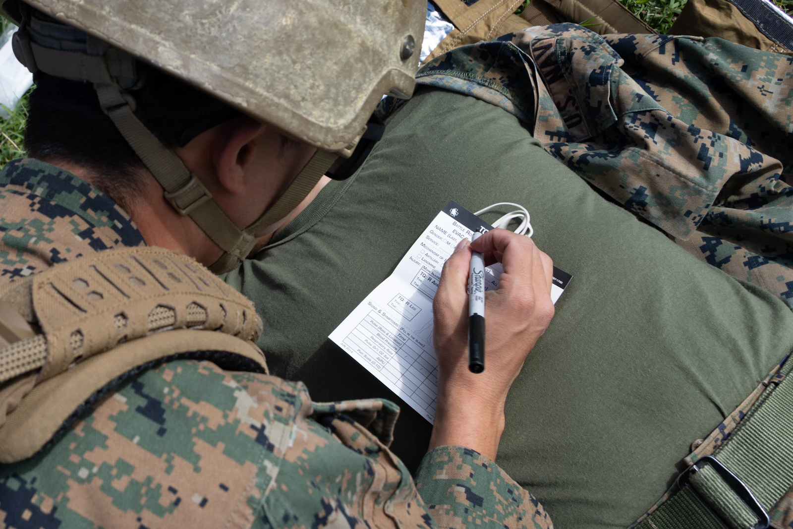 Military service member in camouflage writing on paper during training