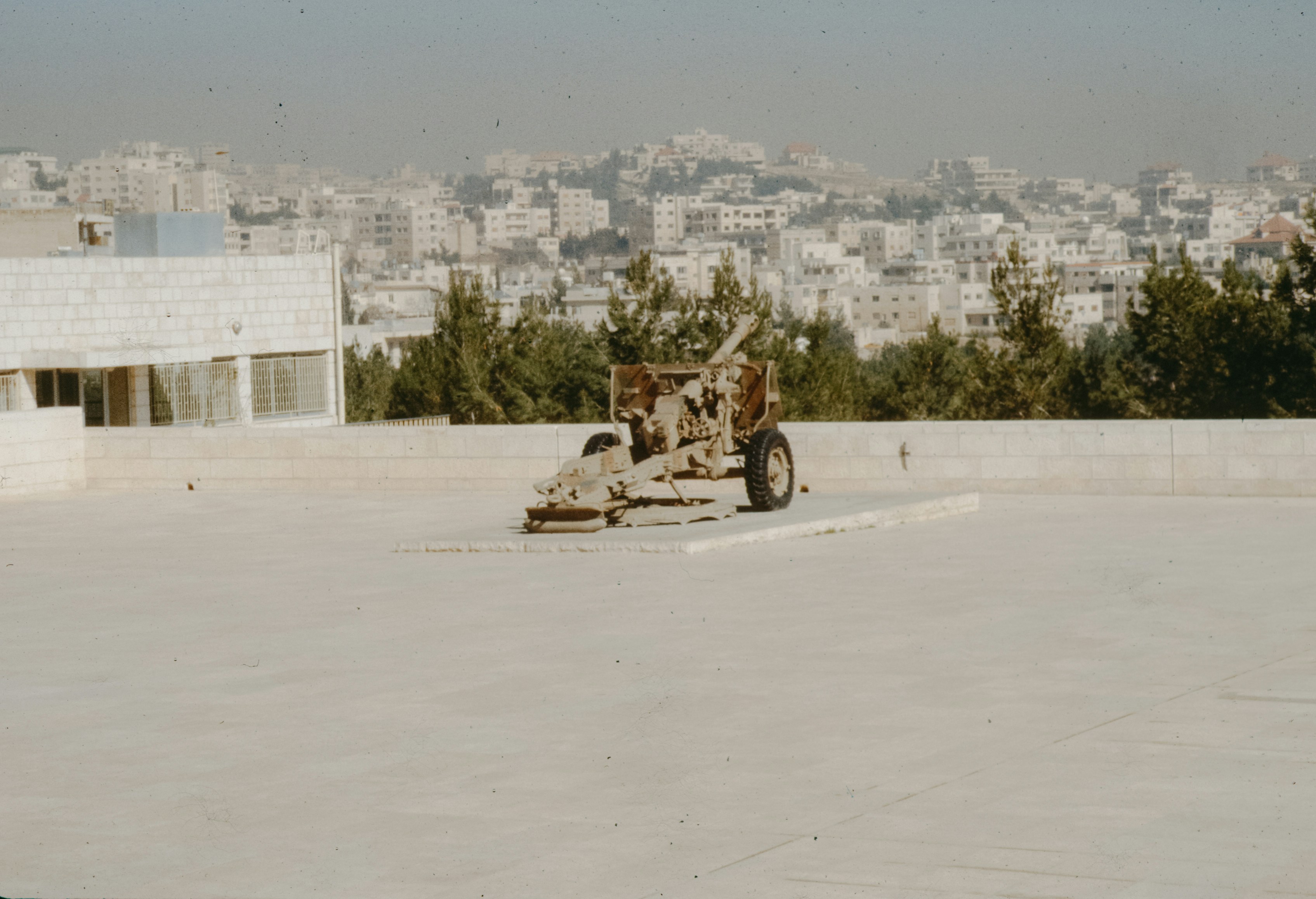 An old cannon sits on a rooftop overlooking a city.