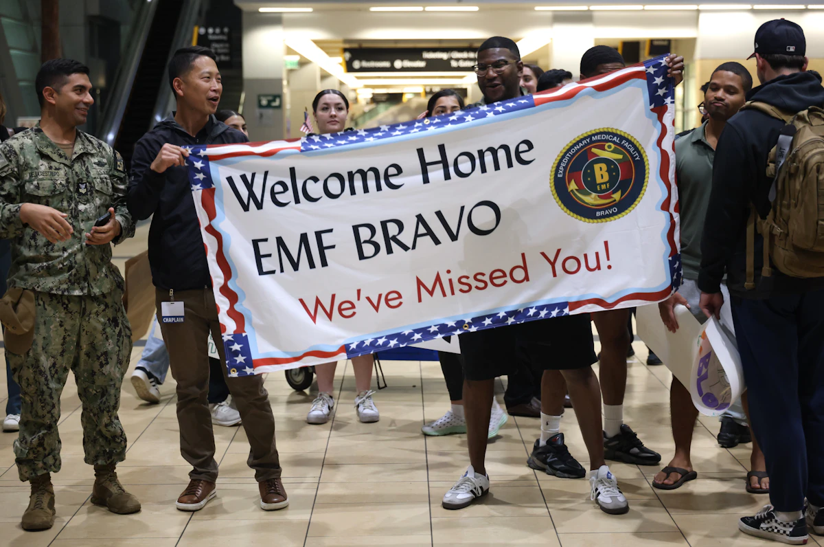 Member of the military in uniform walking through an airport terminal with luggage