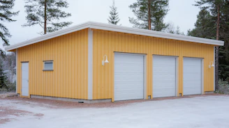 A bright yellow garage with three doors in snow