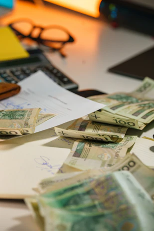 Polish currency scattered on a desk with office supplies.