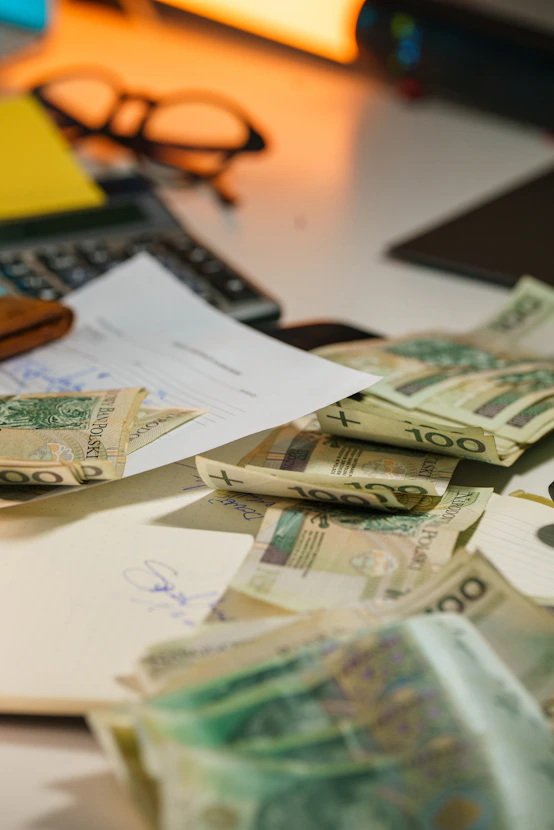 Polish currency scattered on a desk with office supplies.