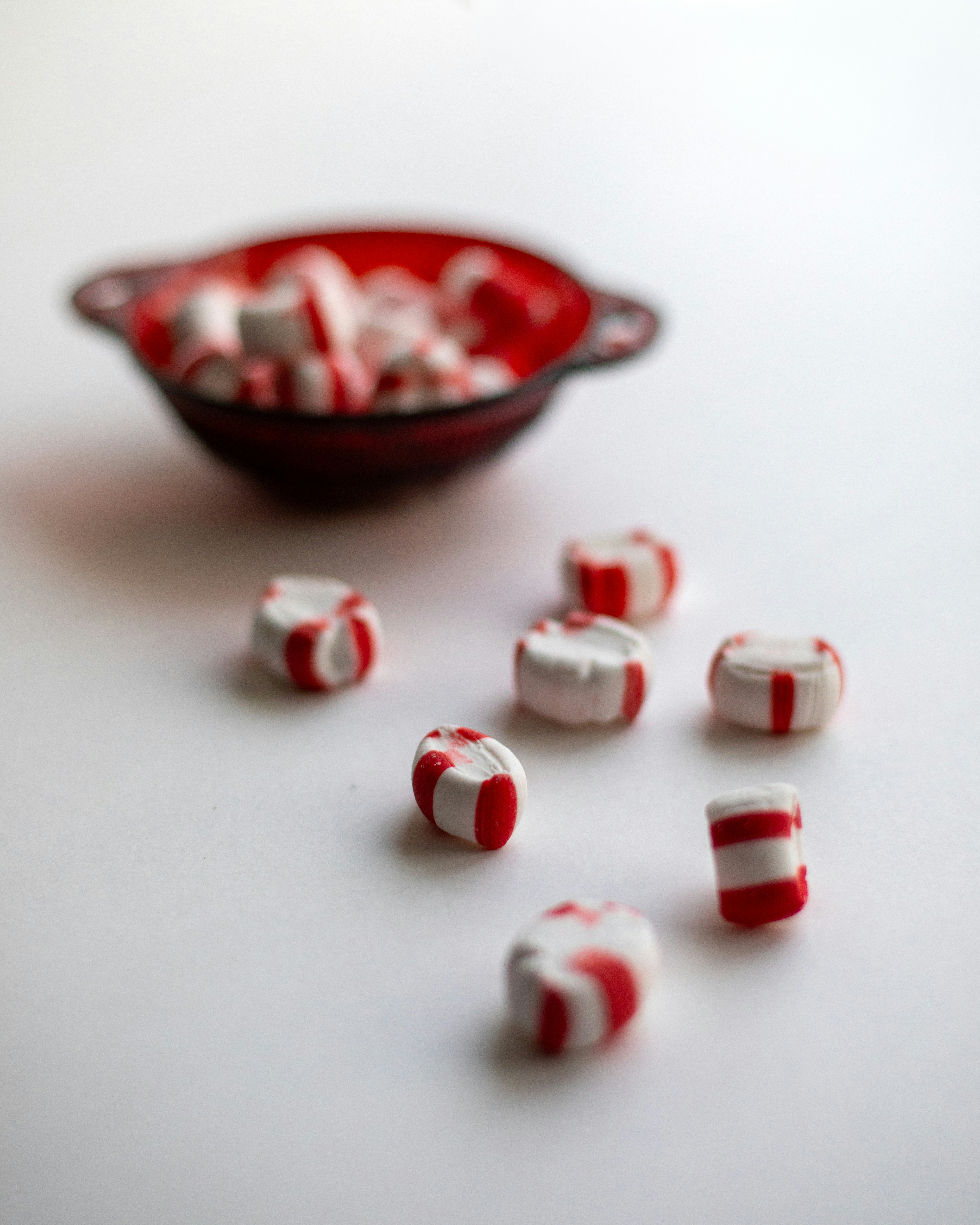 Peppermint candies spilled from a red bowl.