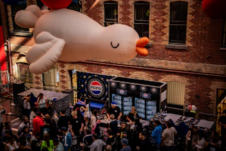 Giant inflatable bird floats over a crowded street event