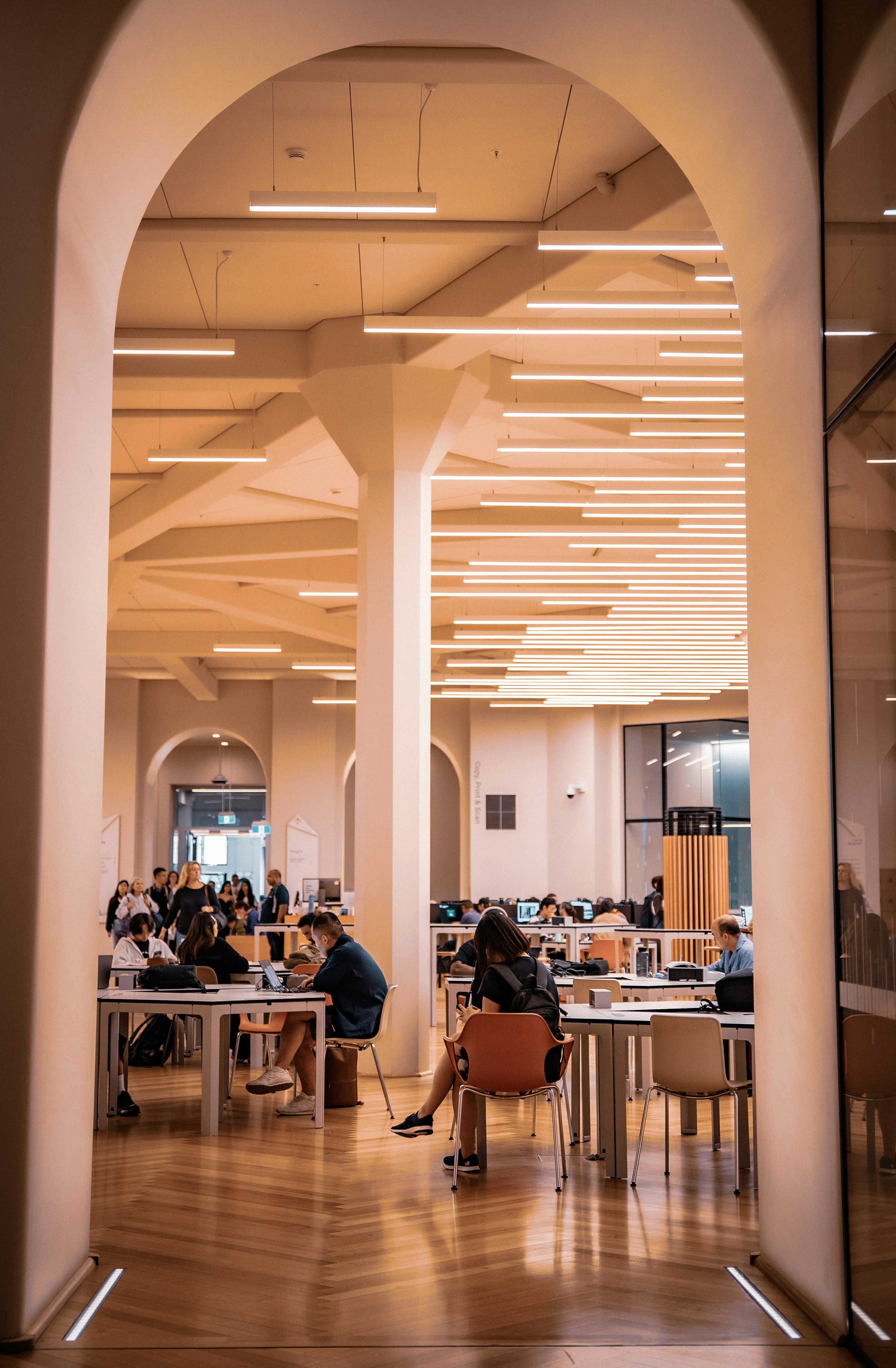 People studying in a large, well-lit library hall.