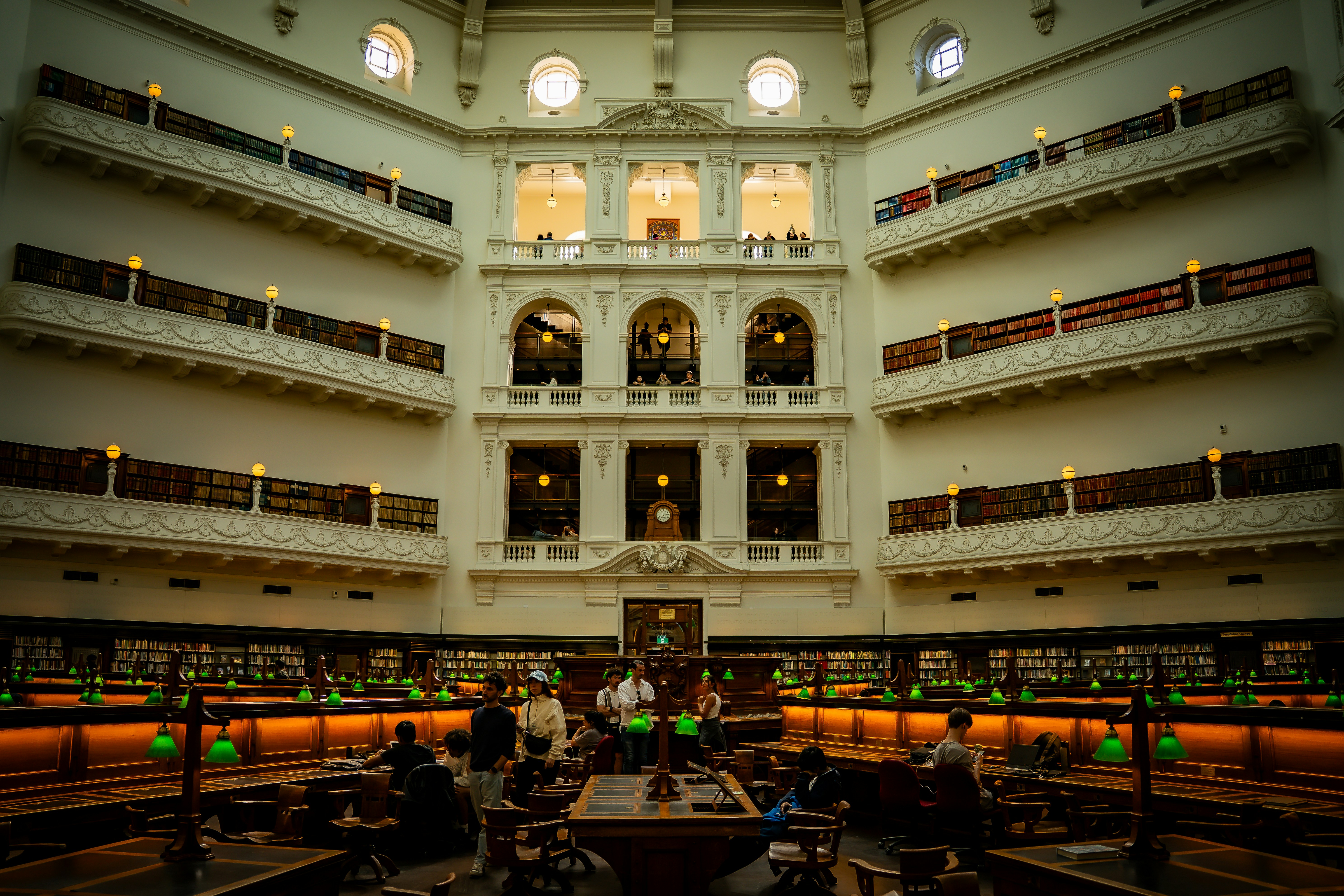 Grand library interior with people reading at tables.