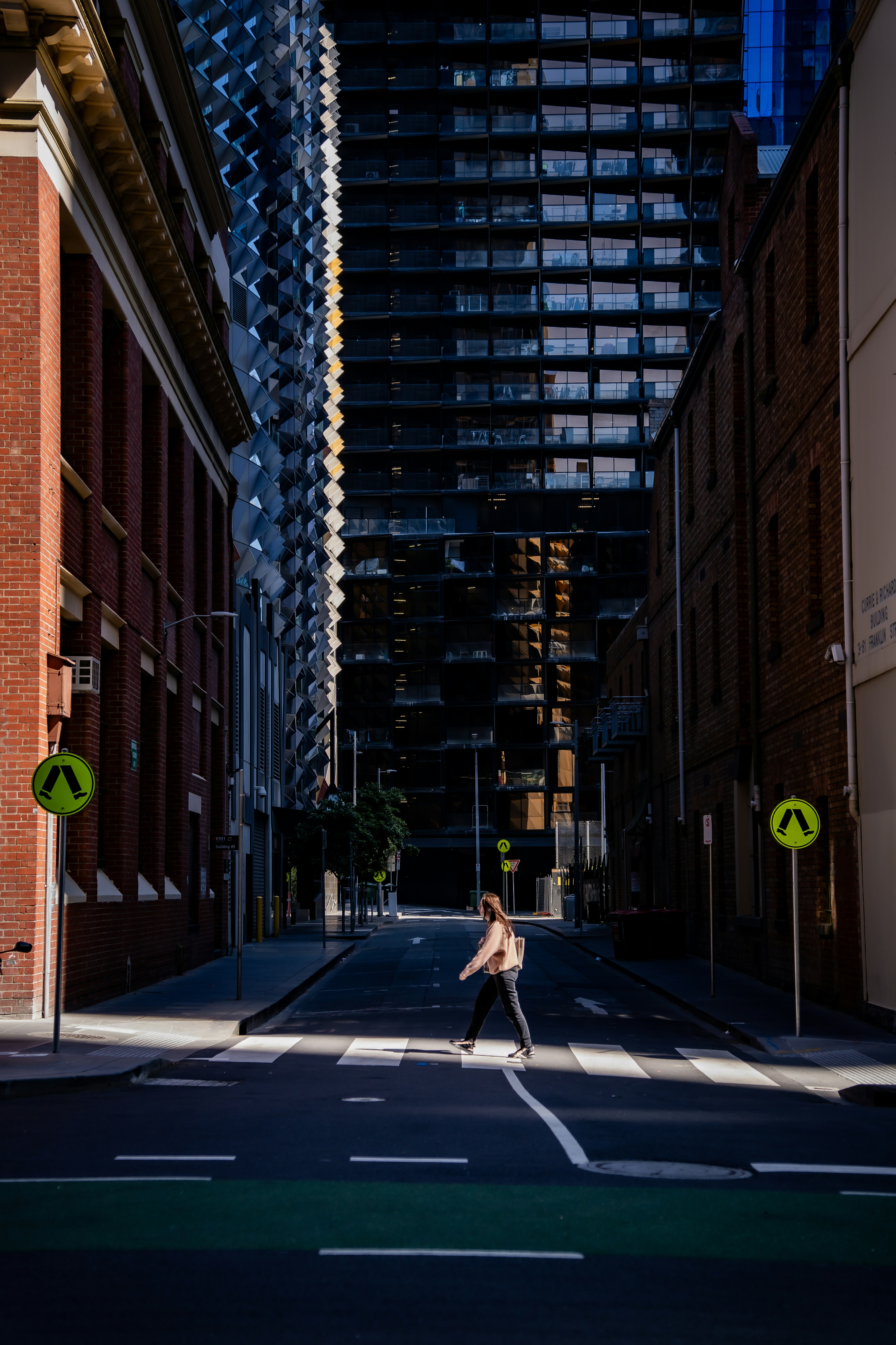 Person crossing street between tall buildings