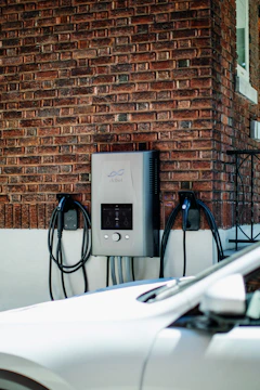 Electric car charging station mounted on brick wall.
