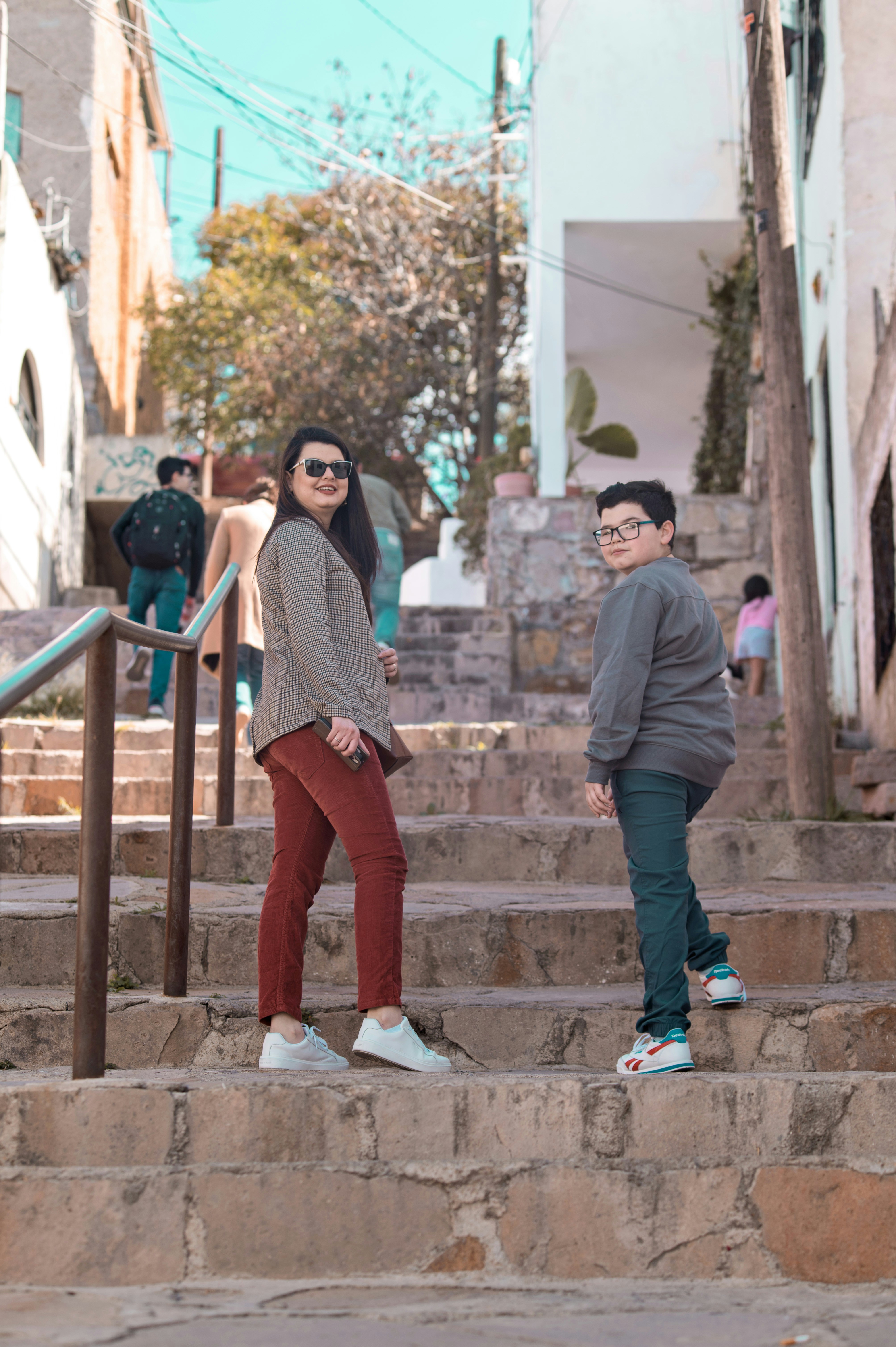 A woman and boy walk up stone steps outdoors.