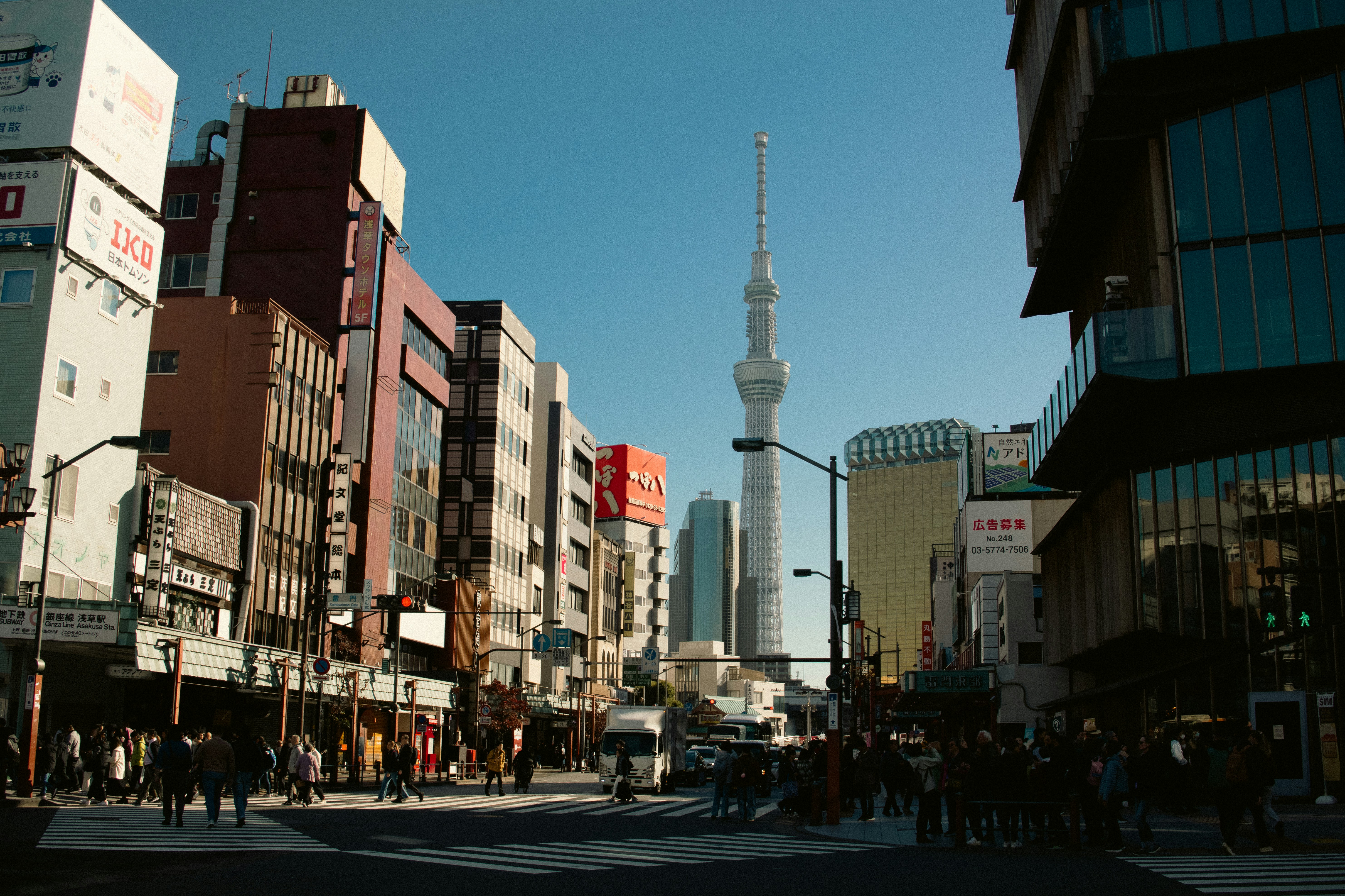Modern city street with tall buildings and a tower.