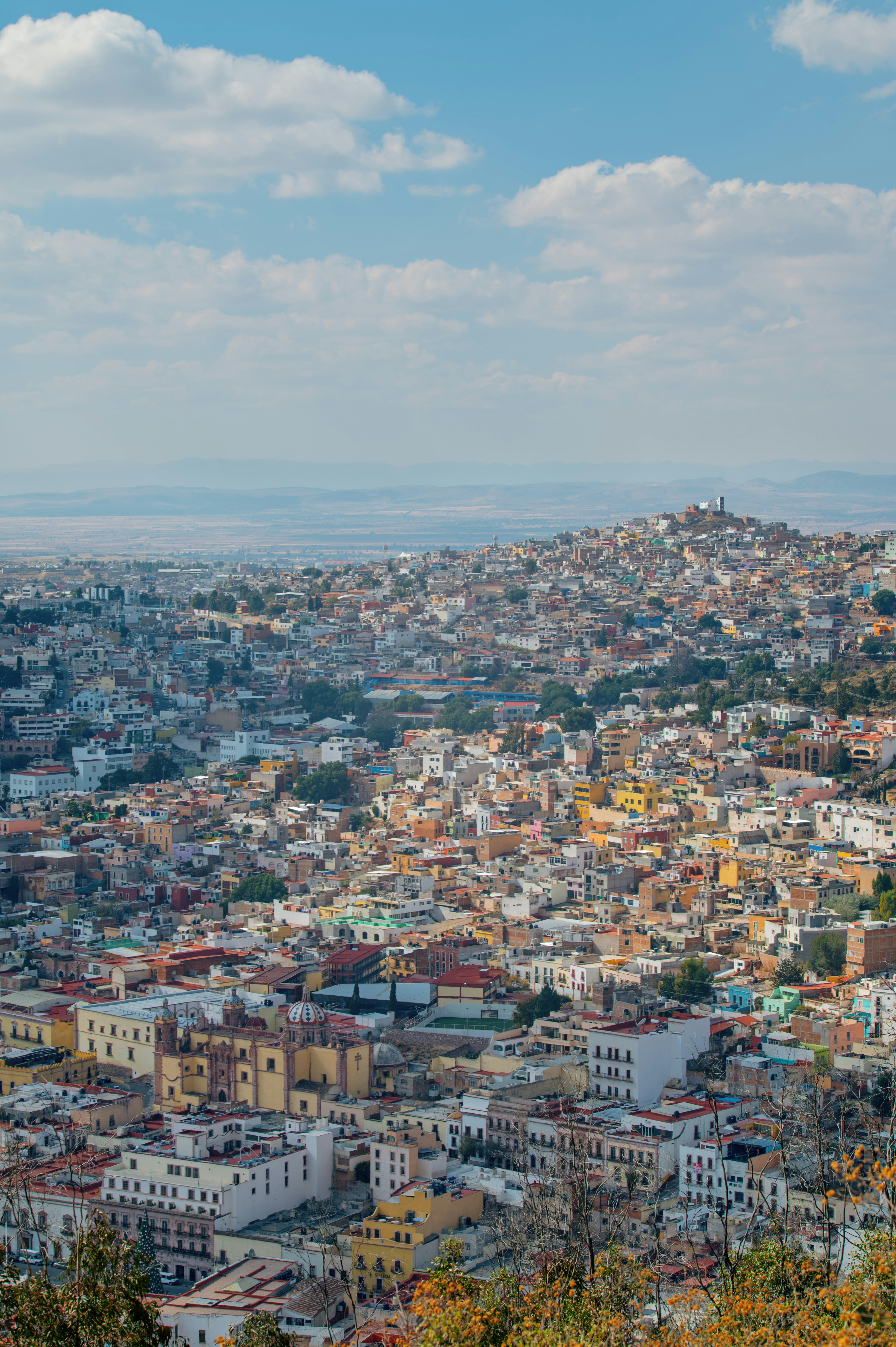 Colorful cityscape on a hillside under a blue sky.