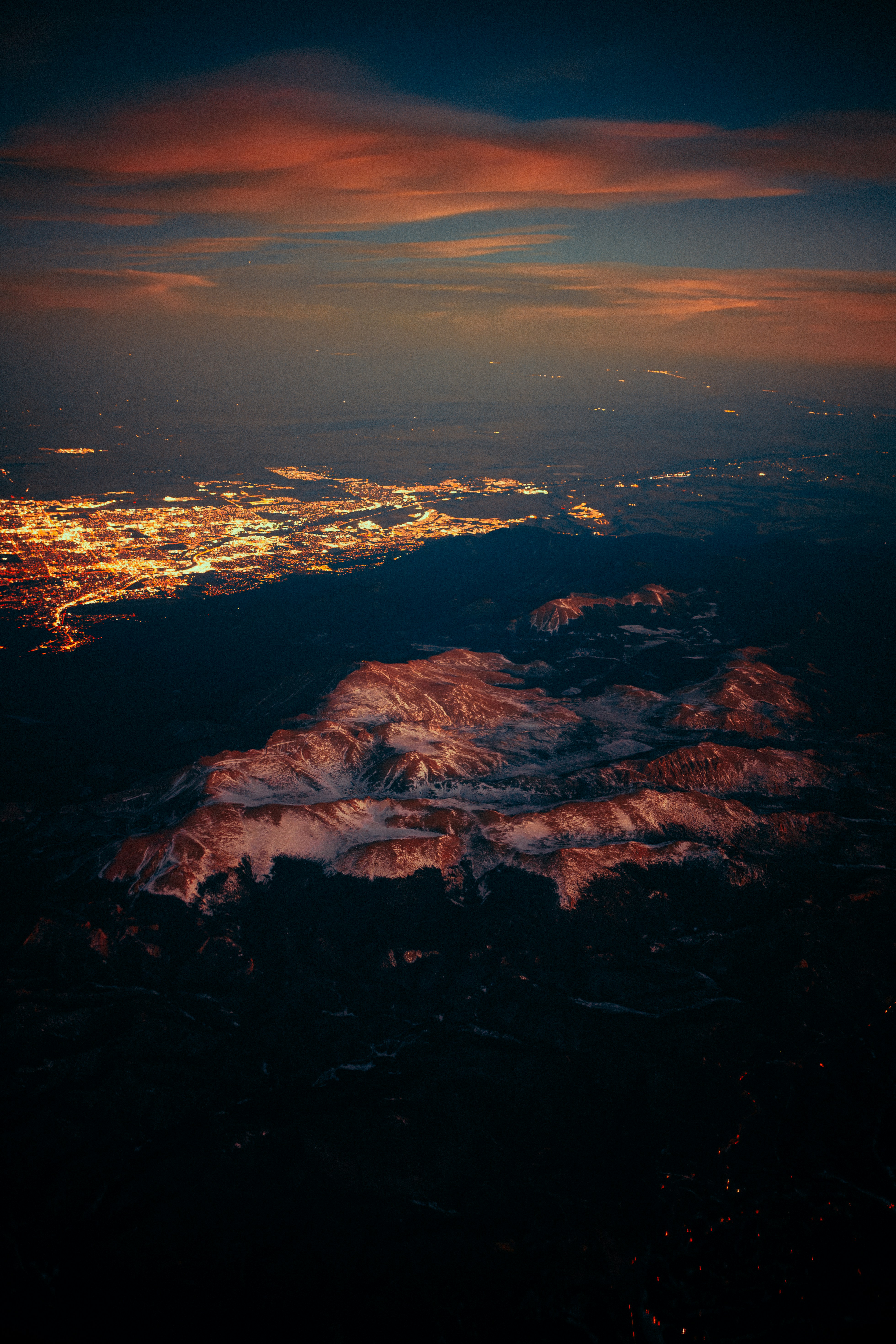 Mountain range illuminated by sunset near city lights