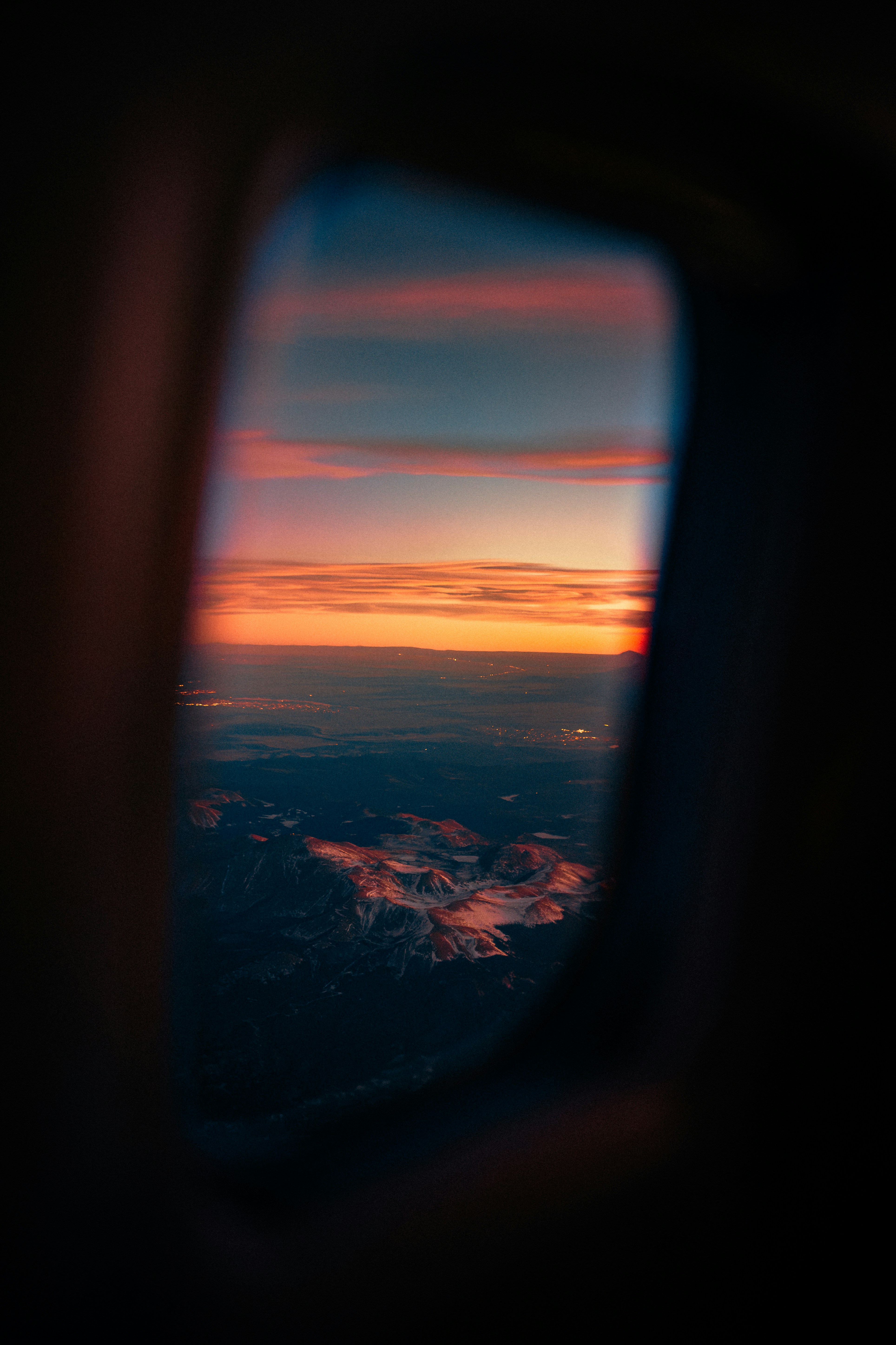 Sunset over mountains seen through airplane window
