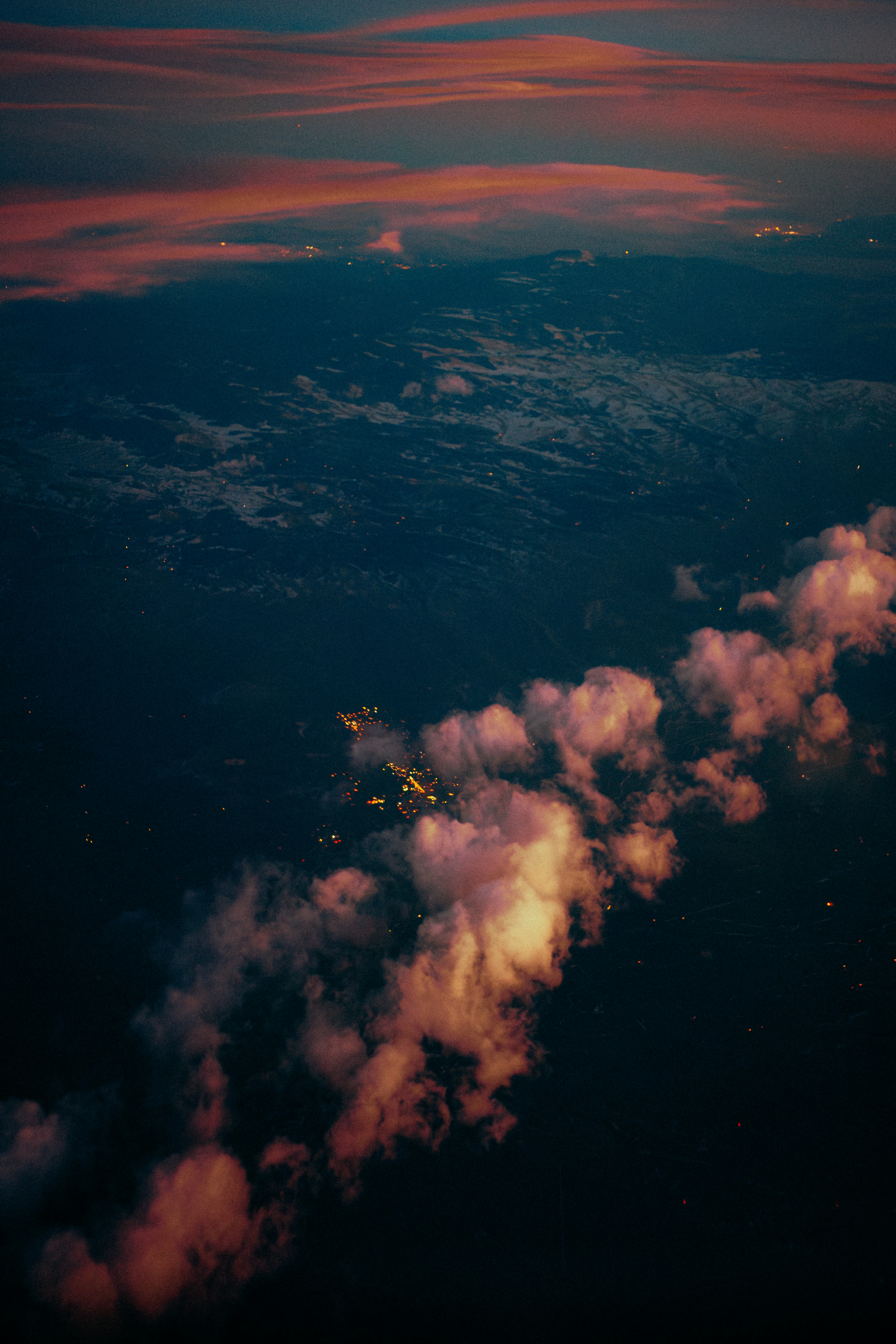 Clouds illuminated by city lights at dusk from above
