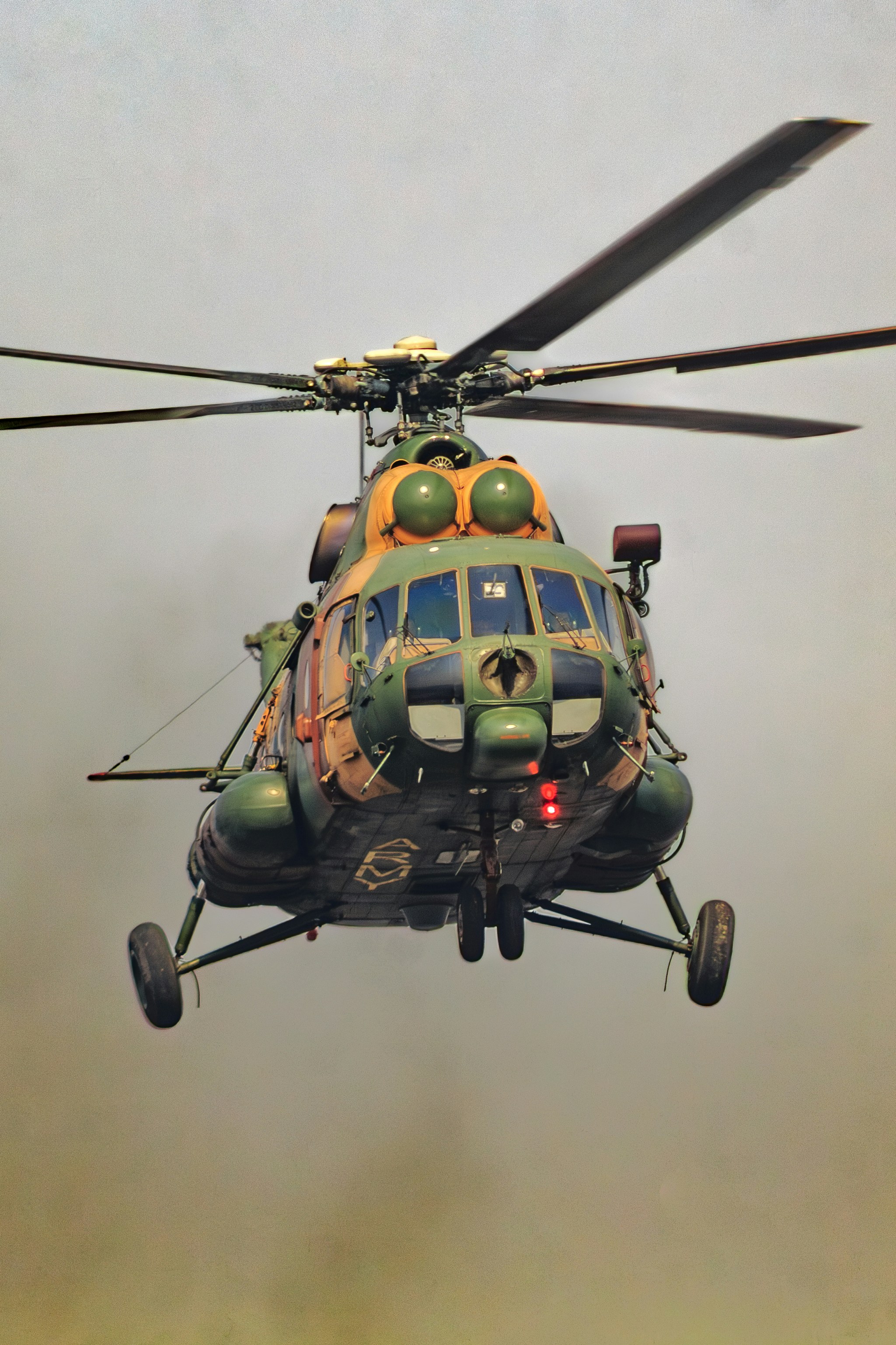 A military helicopter in flight against a hazy sky.