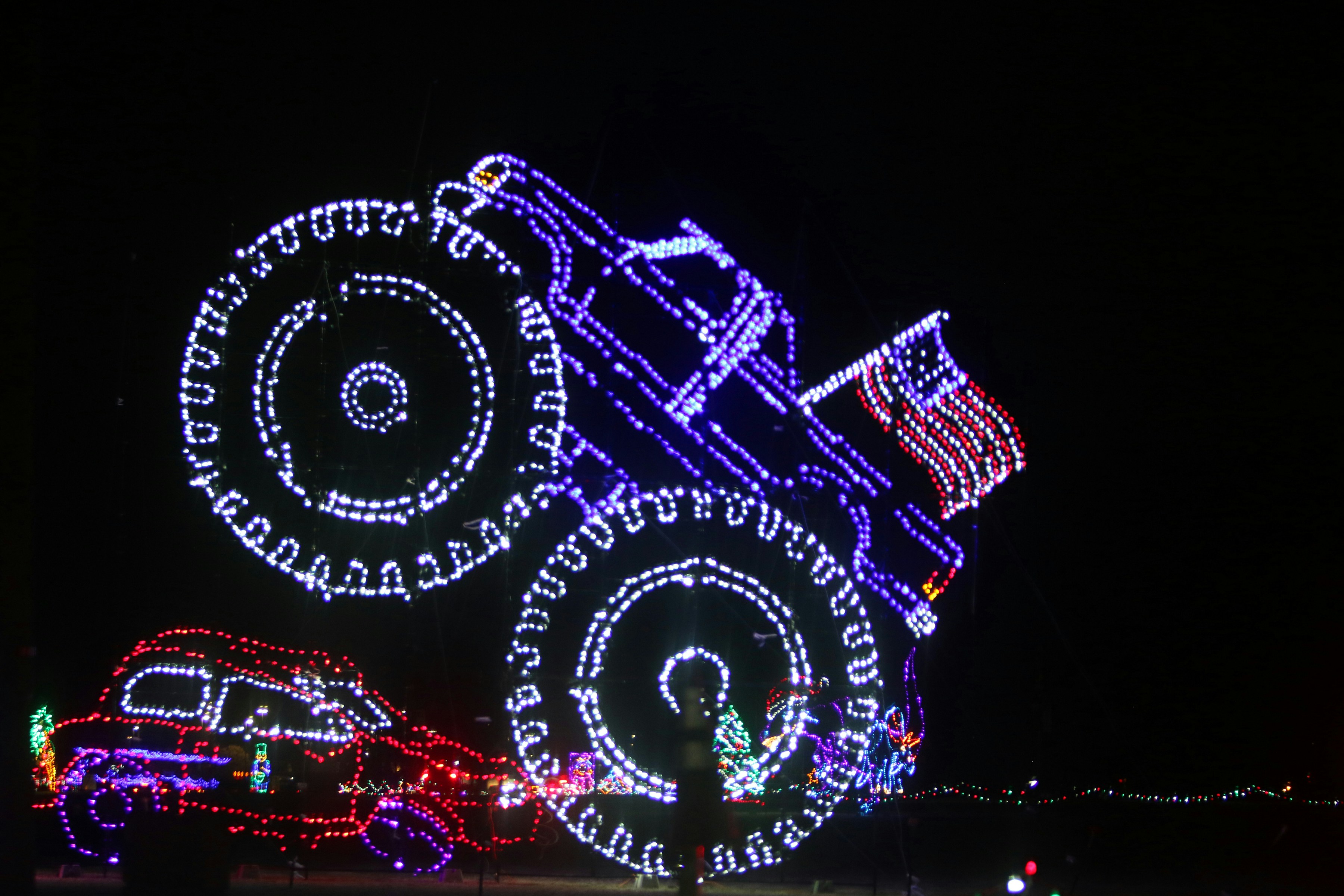 Monster truck and car made of christmas lights.