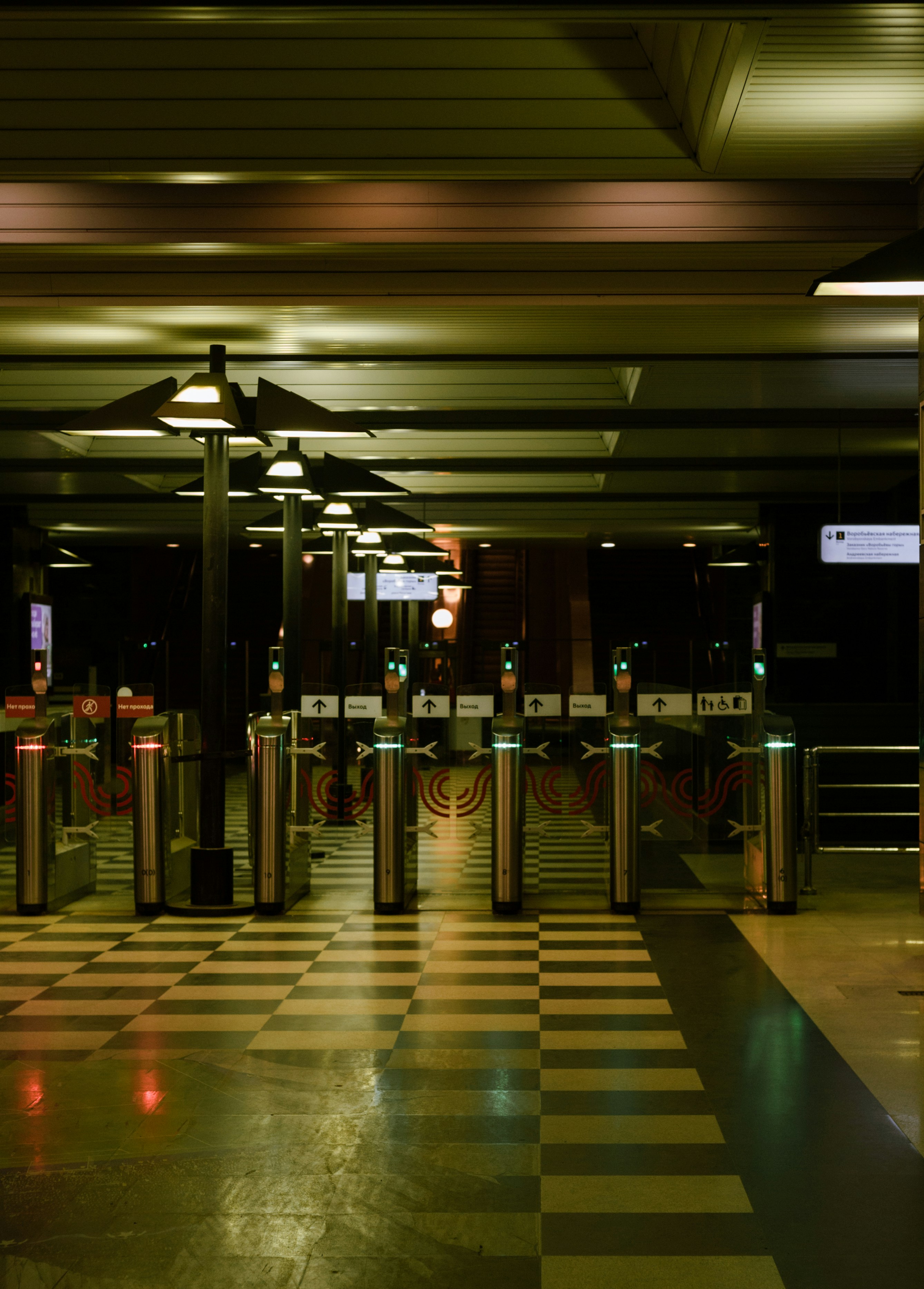 Turnstiles in a dimly lit subway station at night.