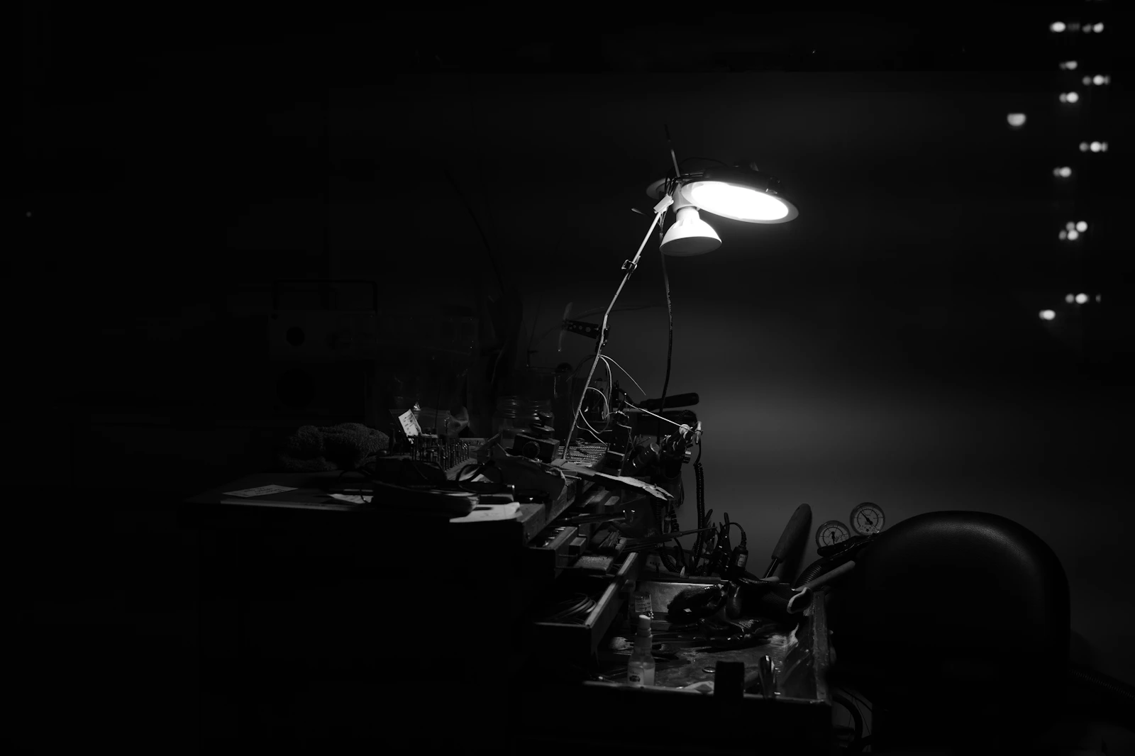 A desk lamp illuminating a cluttered late-night workspace