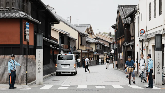 A van and cyclist pass along the narrow, traditional machiya-lined Hanamikoji Street.