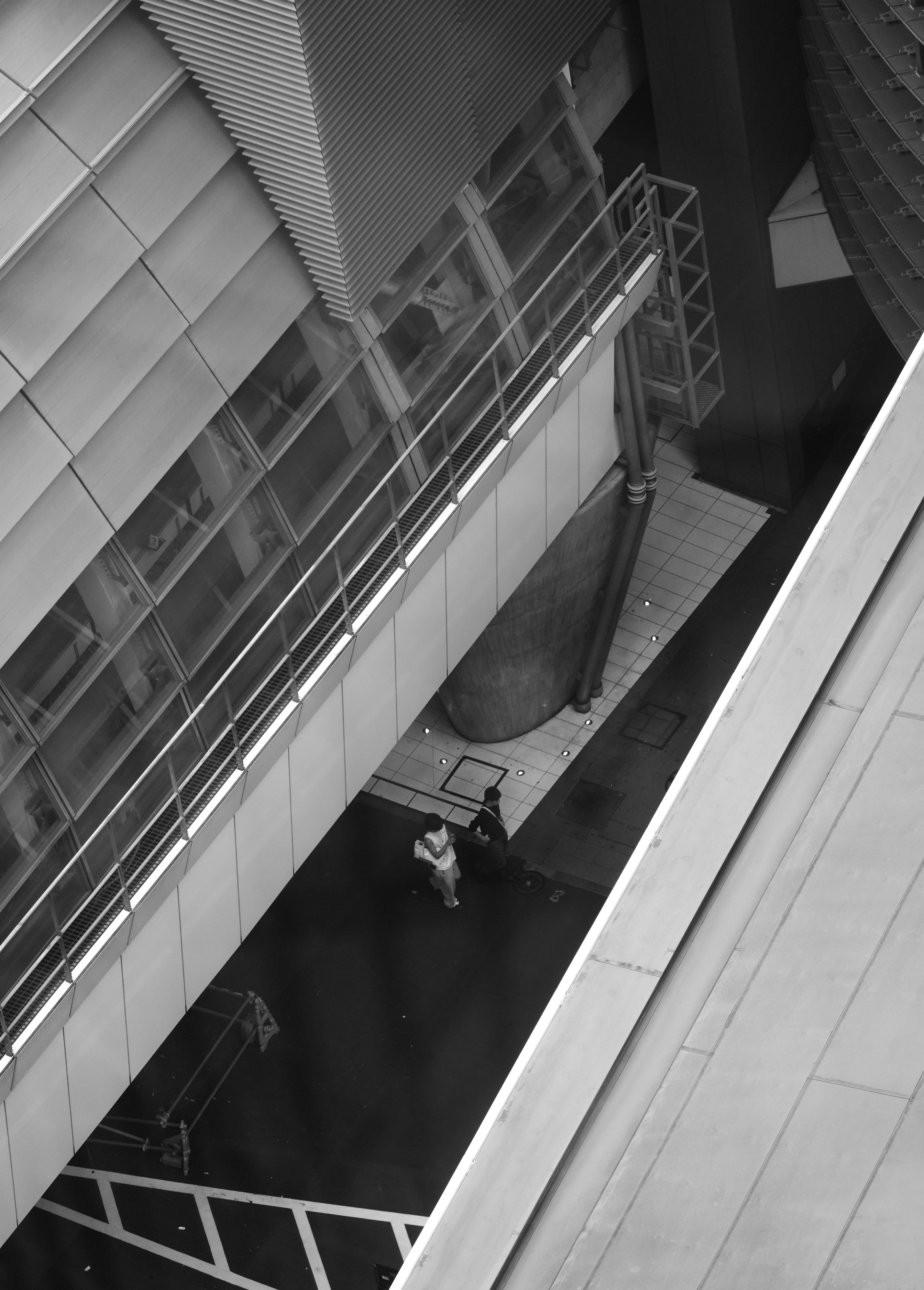 Two people walk on a wet city sidewalk.