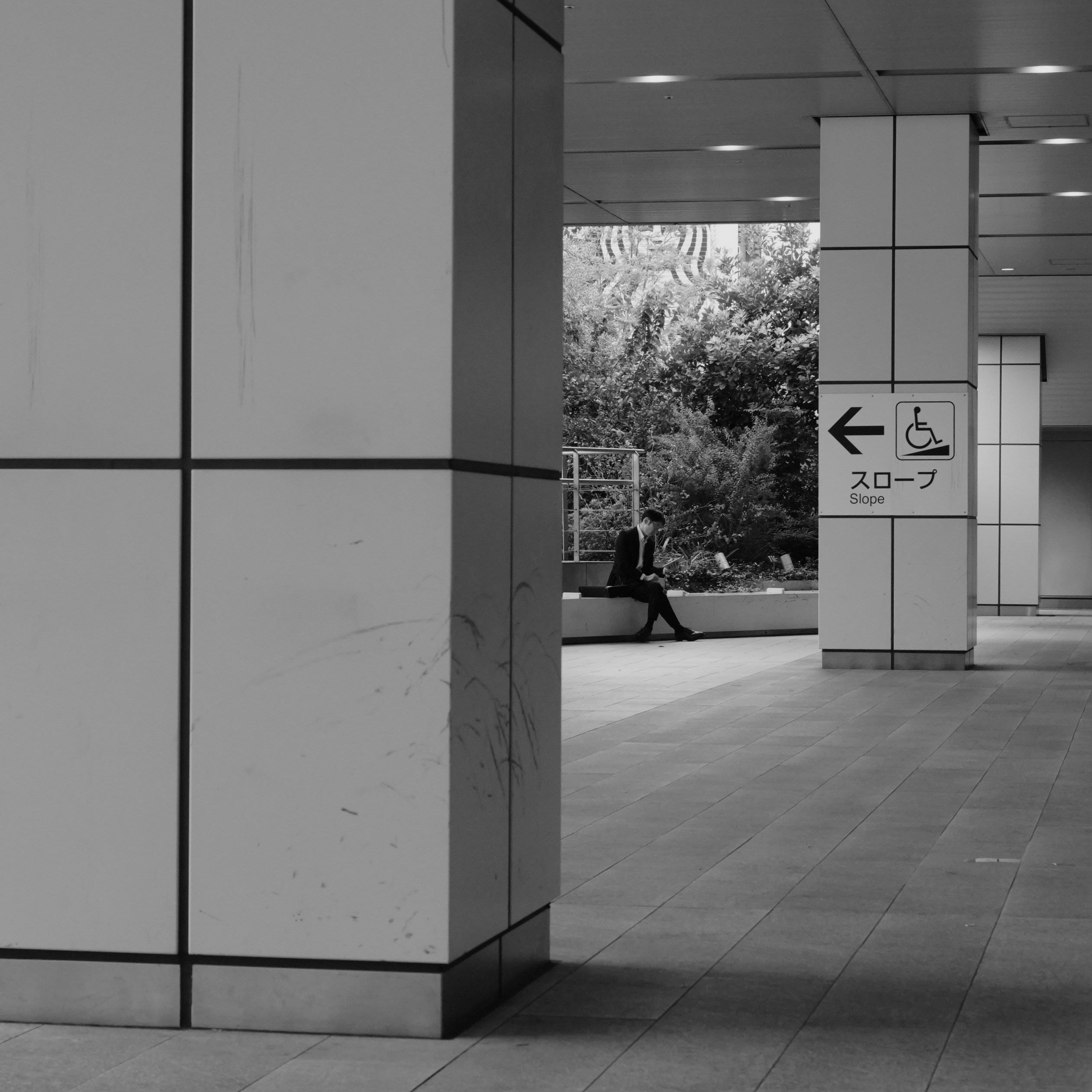 Person sitting on bench near modern building columns