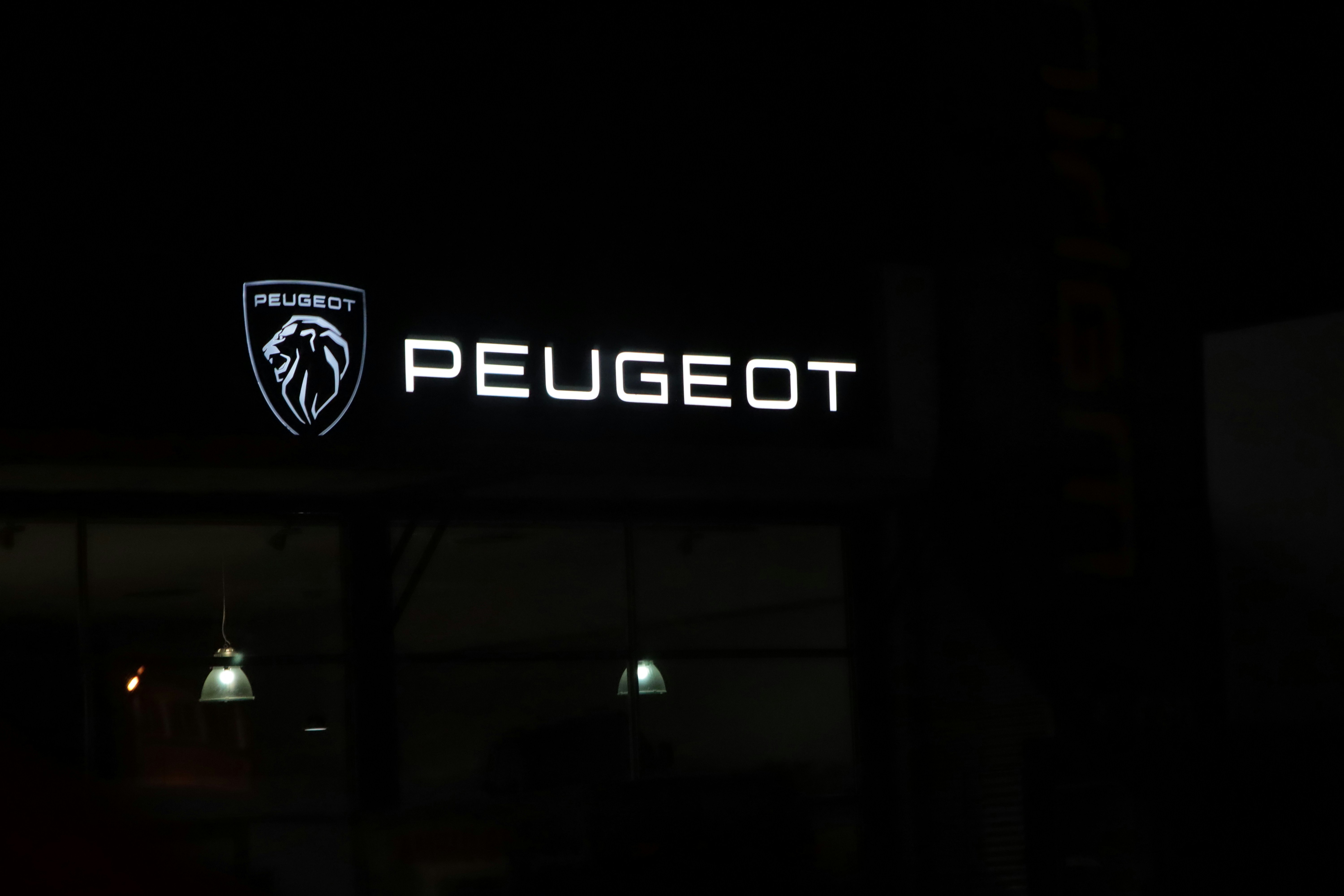 Peugeot logo illuminated at night on a building