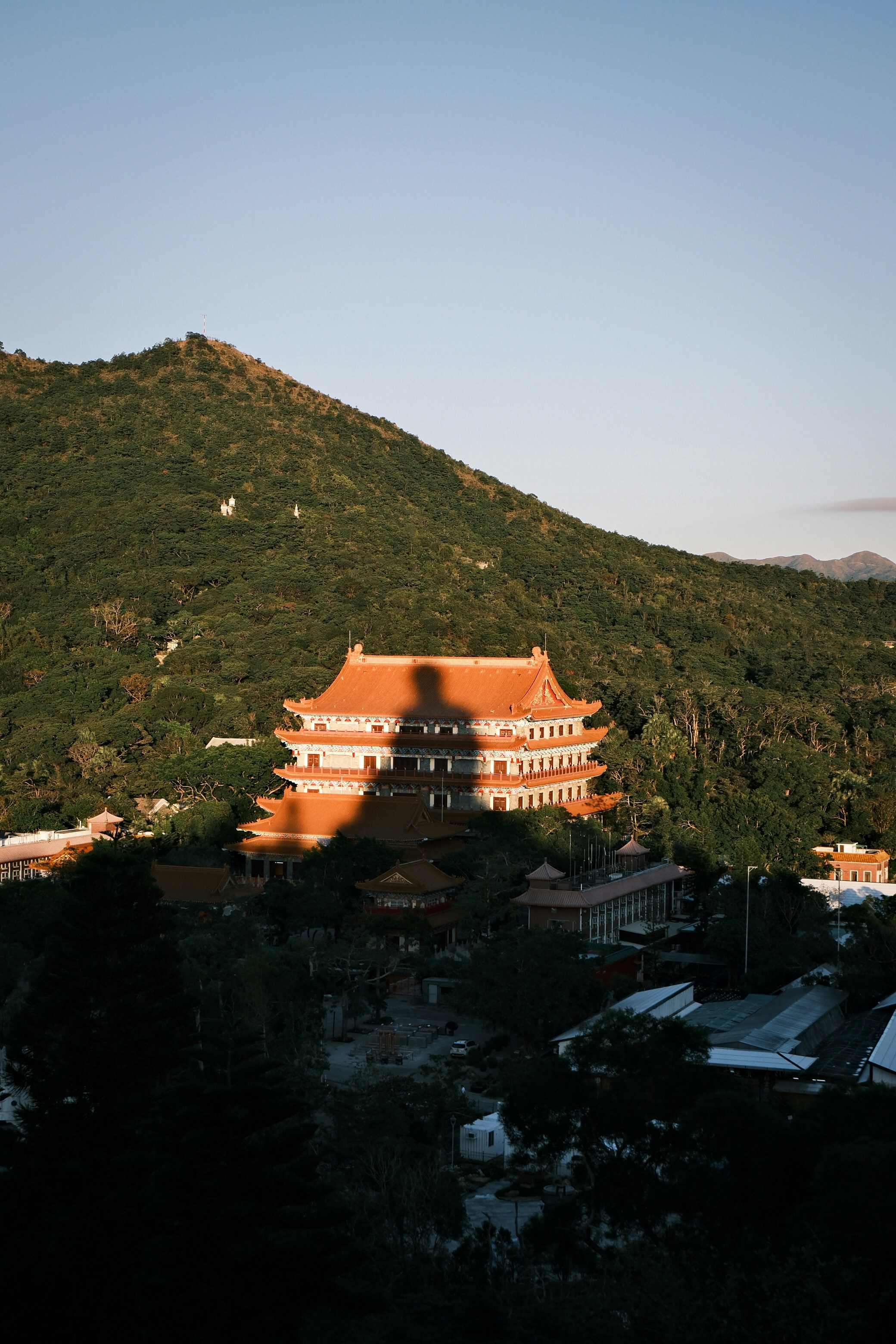 Temple nestled in a lush green mountainside at sunset.