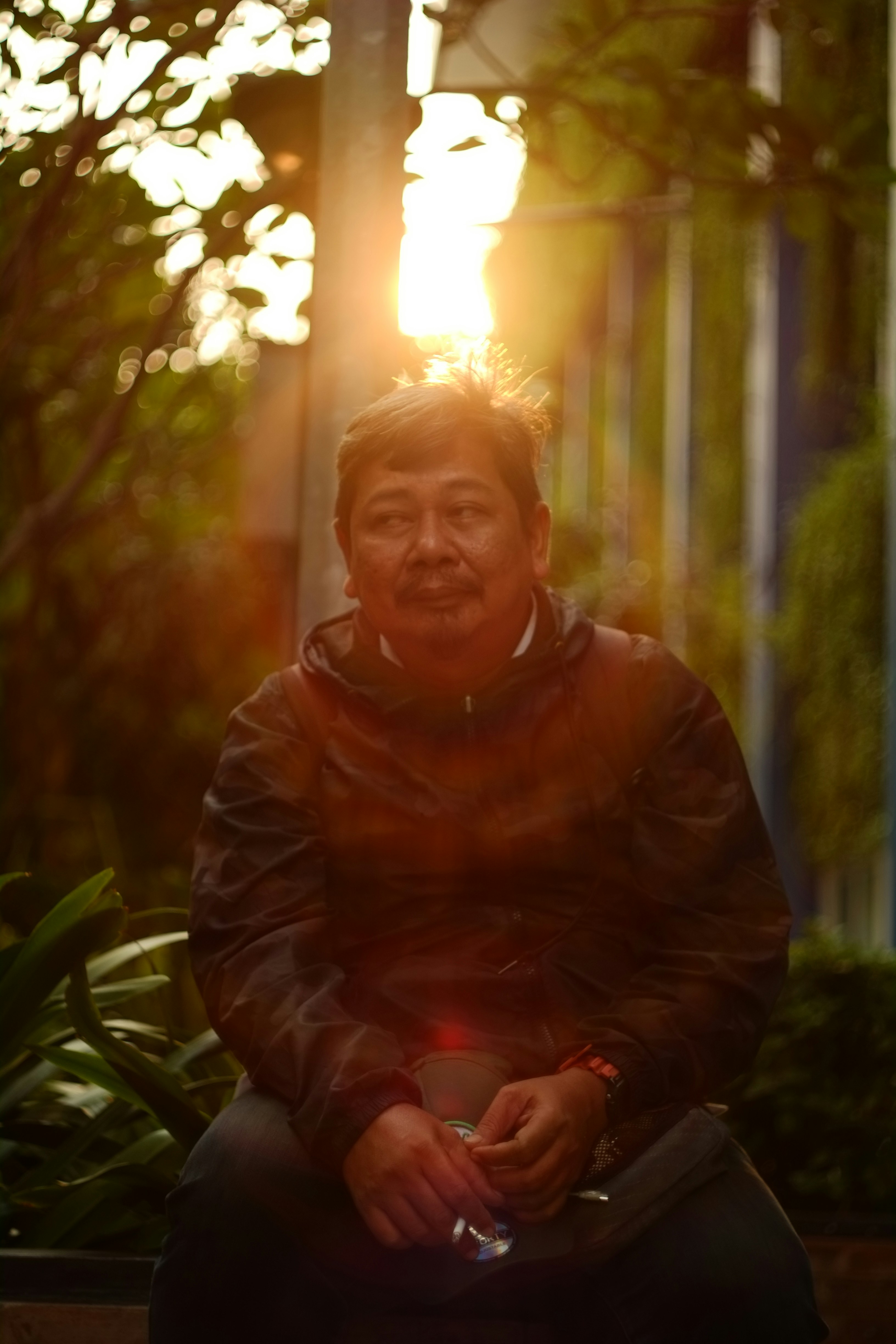 Man sitting outdoors with sun flare behind him