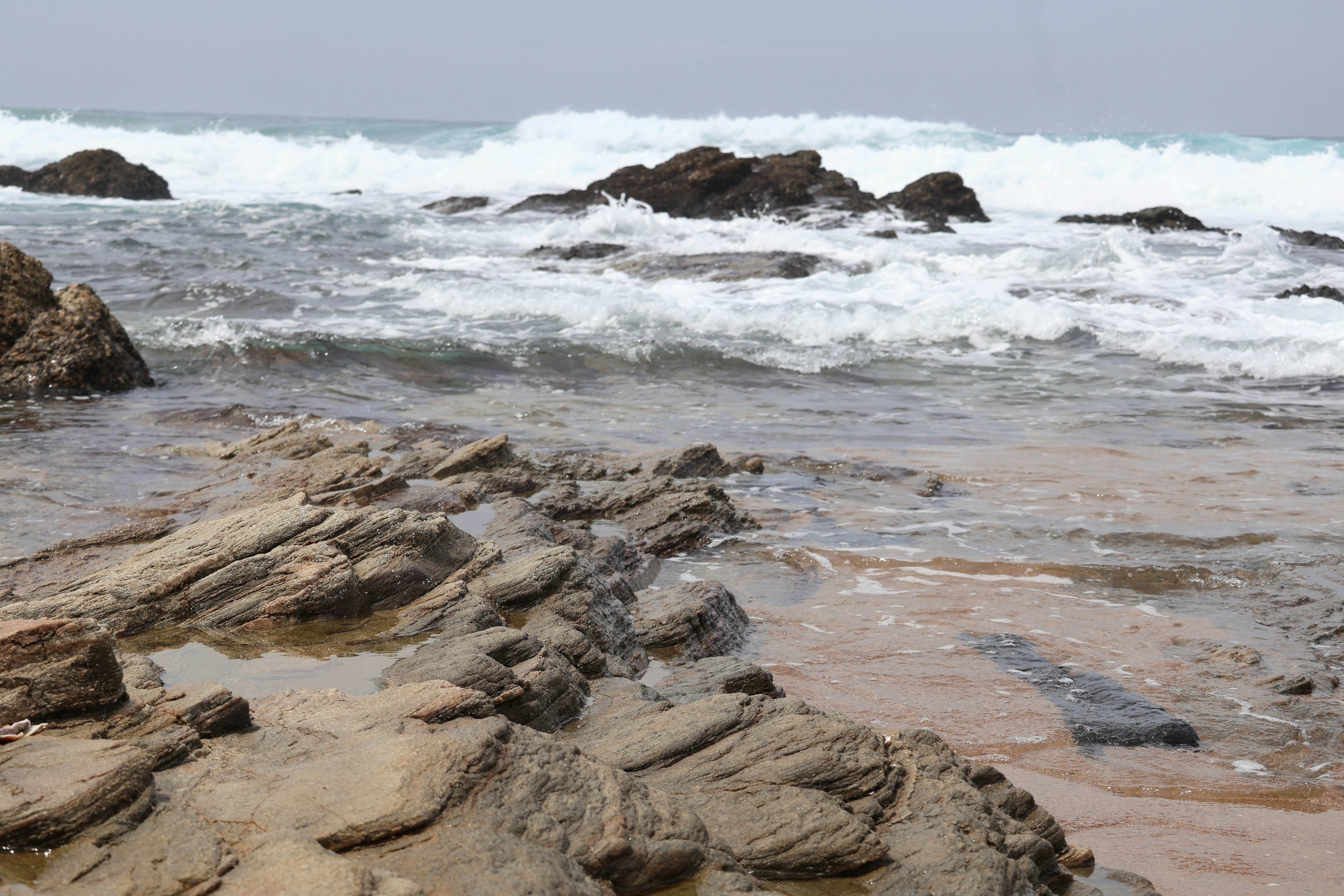 A single stone standing firm against ocean waves, representing the power of refusal