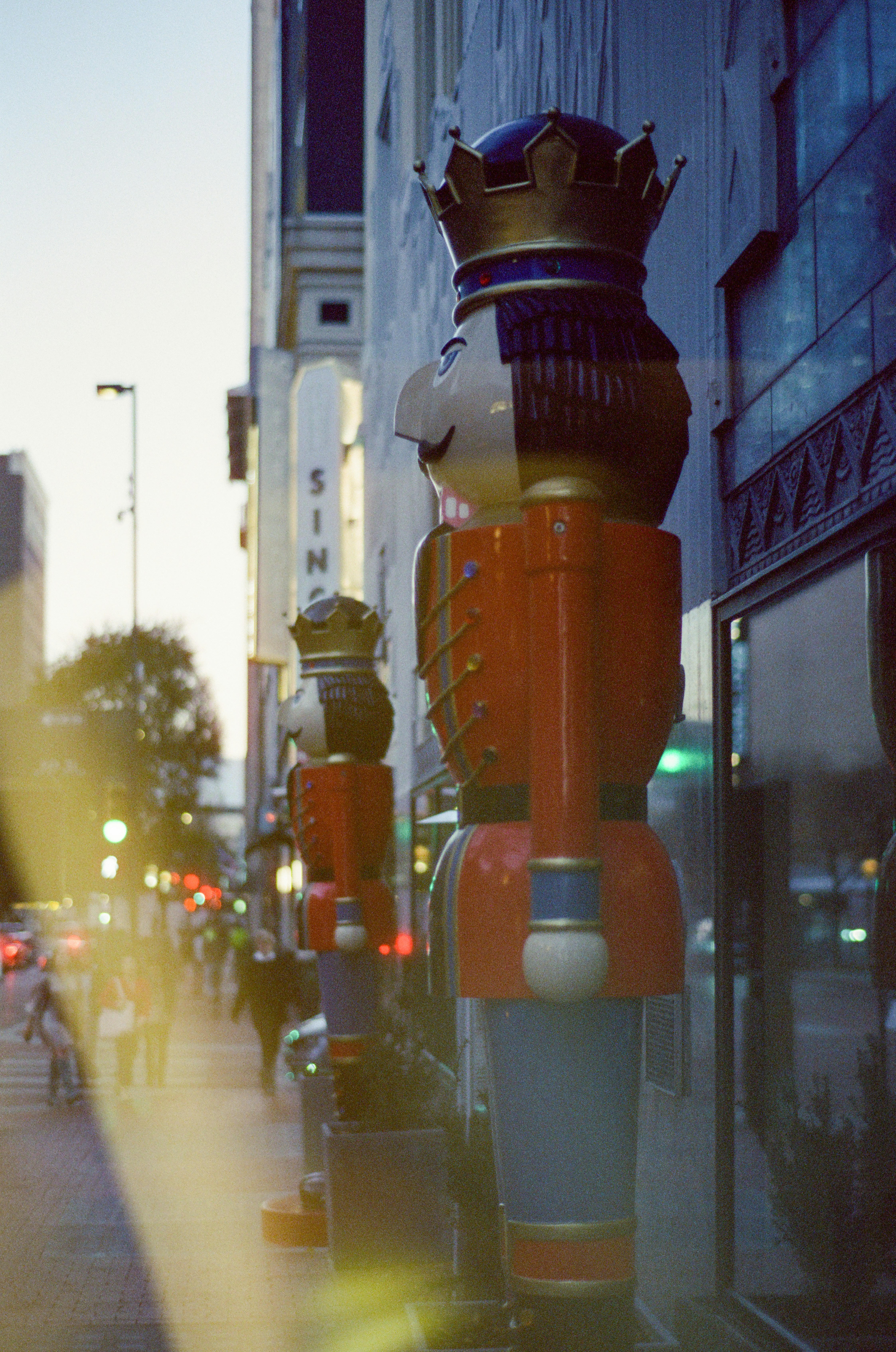 Nutcracker figures line a city sidewalk at dusk