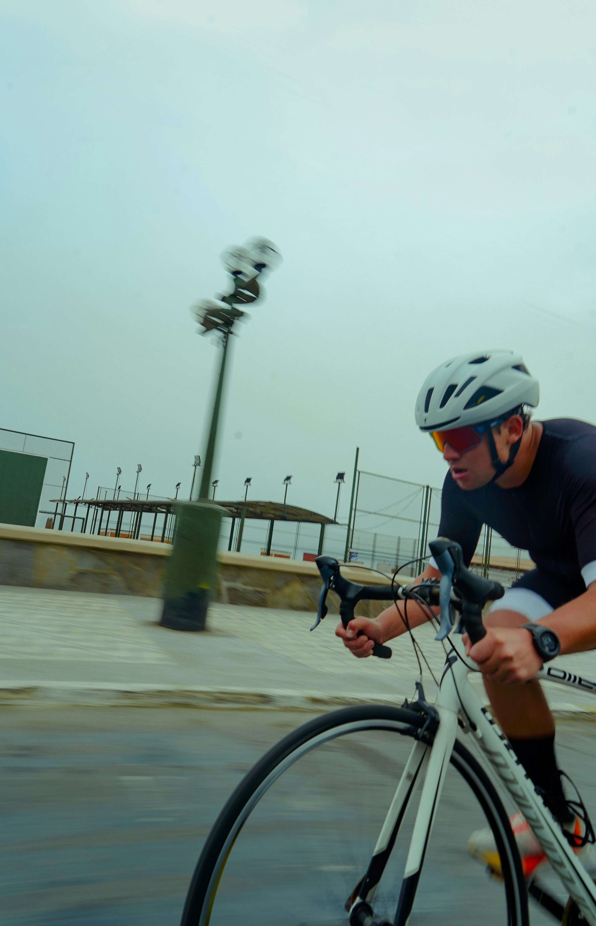 Cyclist wearing helmet riding a white bicycle outdoors