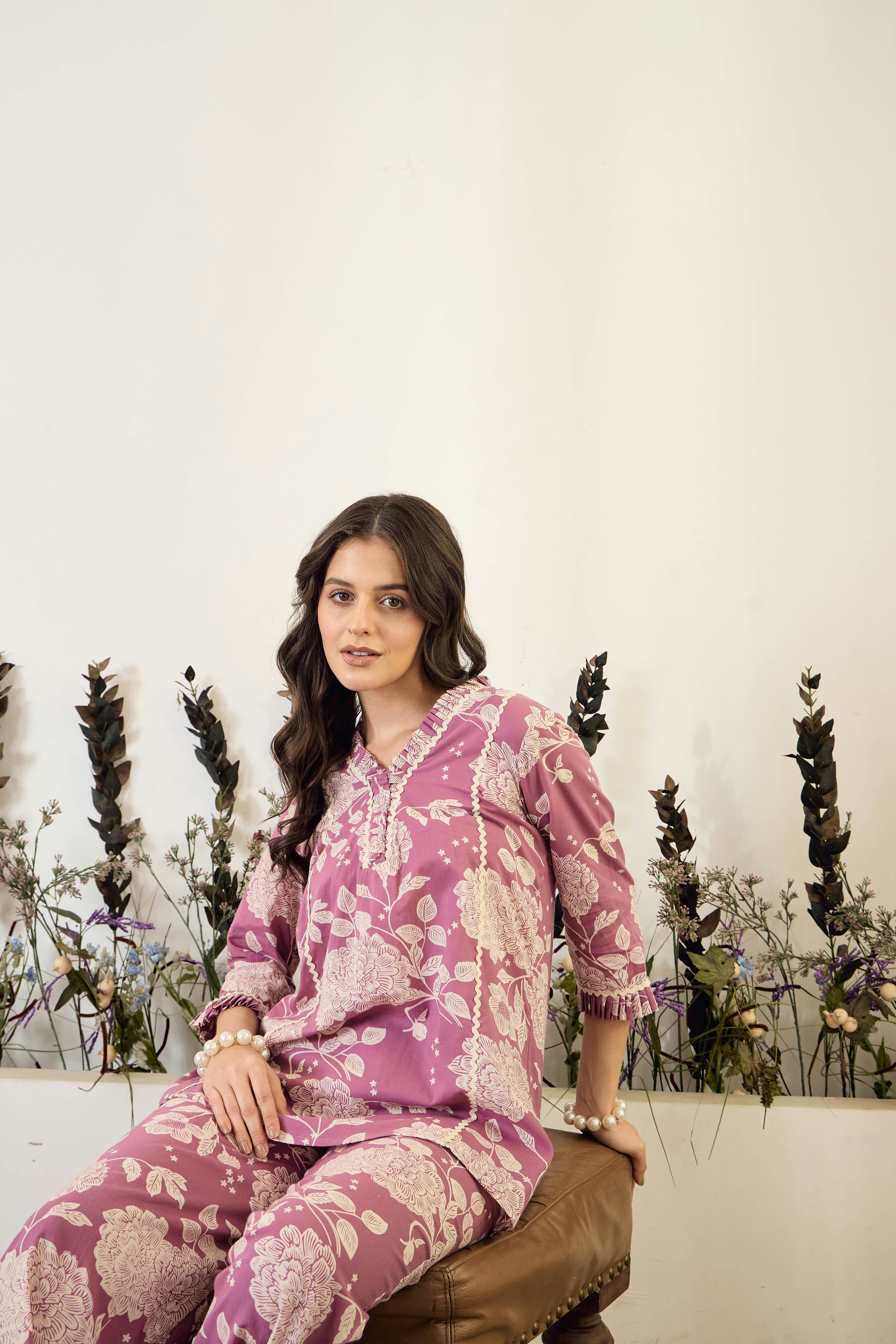 Young woman in floral print outfit sitting indoors.
