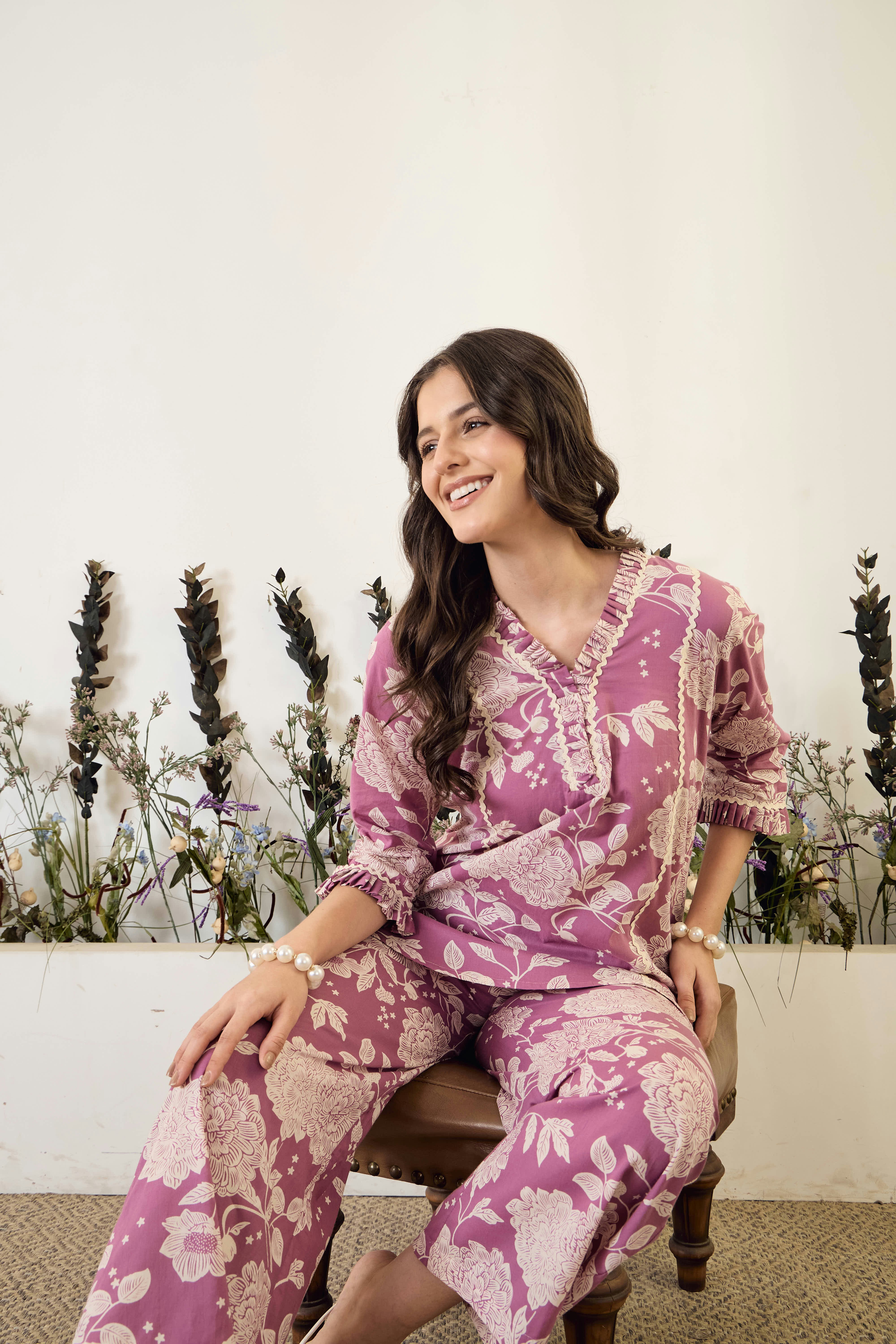 Young woman wearing floral pajamas sitting on stool