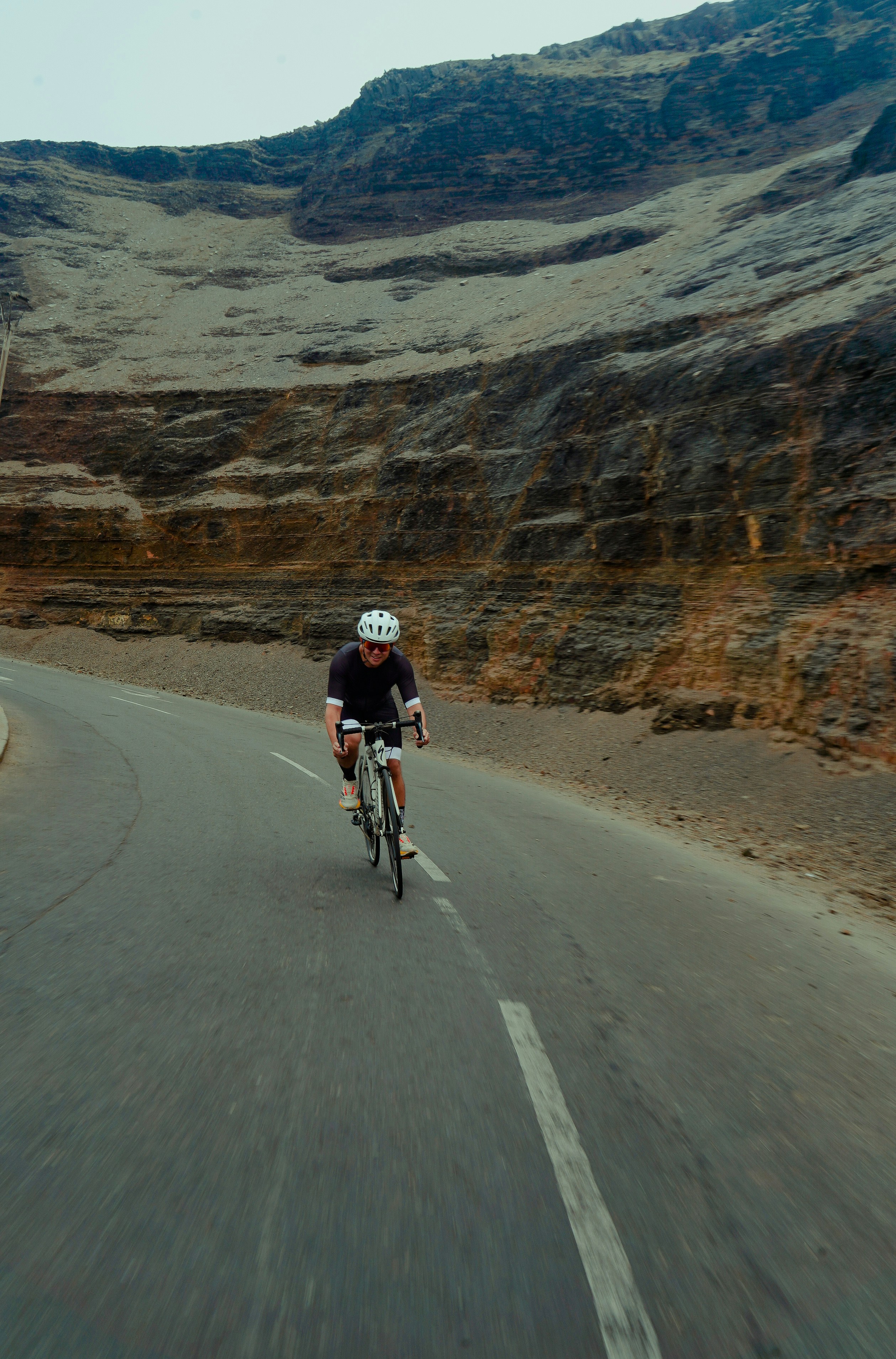 Cyclist riding on a winding road near mountains