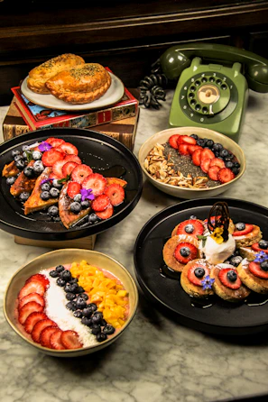 Four delicious breakfast dishes with fruit and toppings.