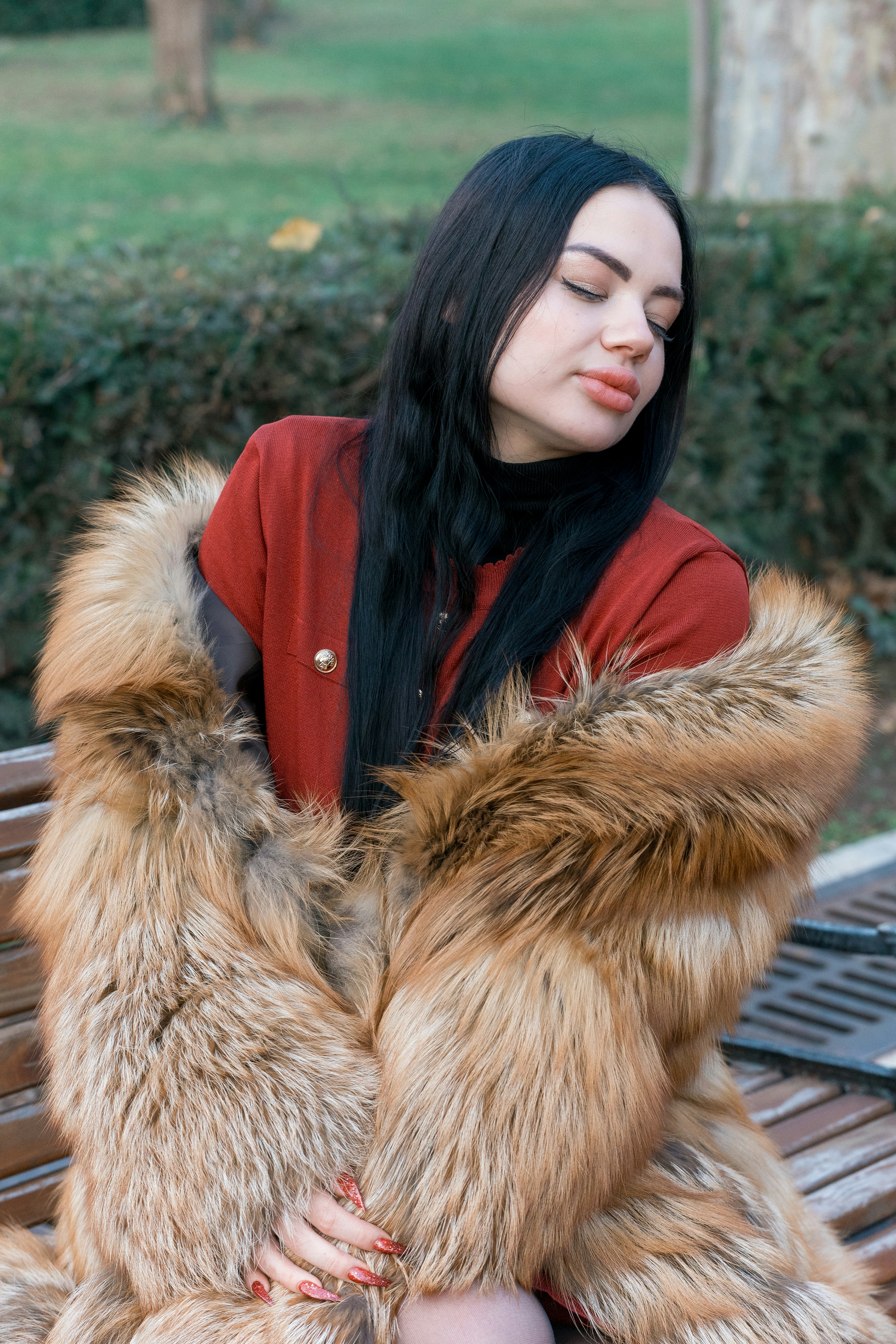 Woman in fur coat sitting on park bench