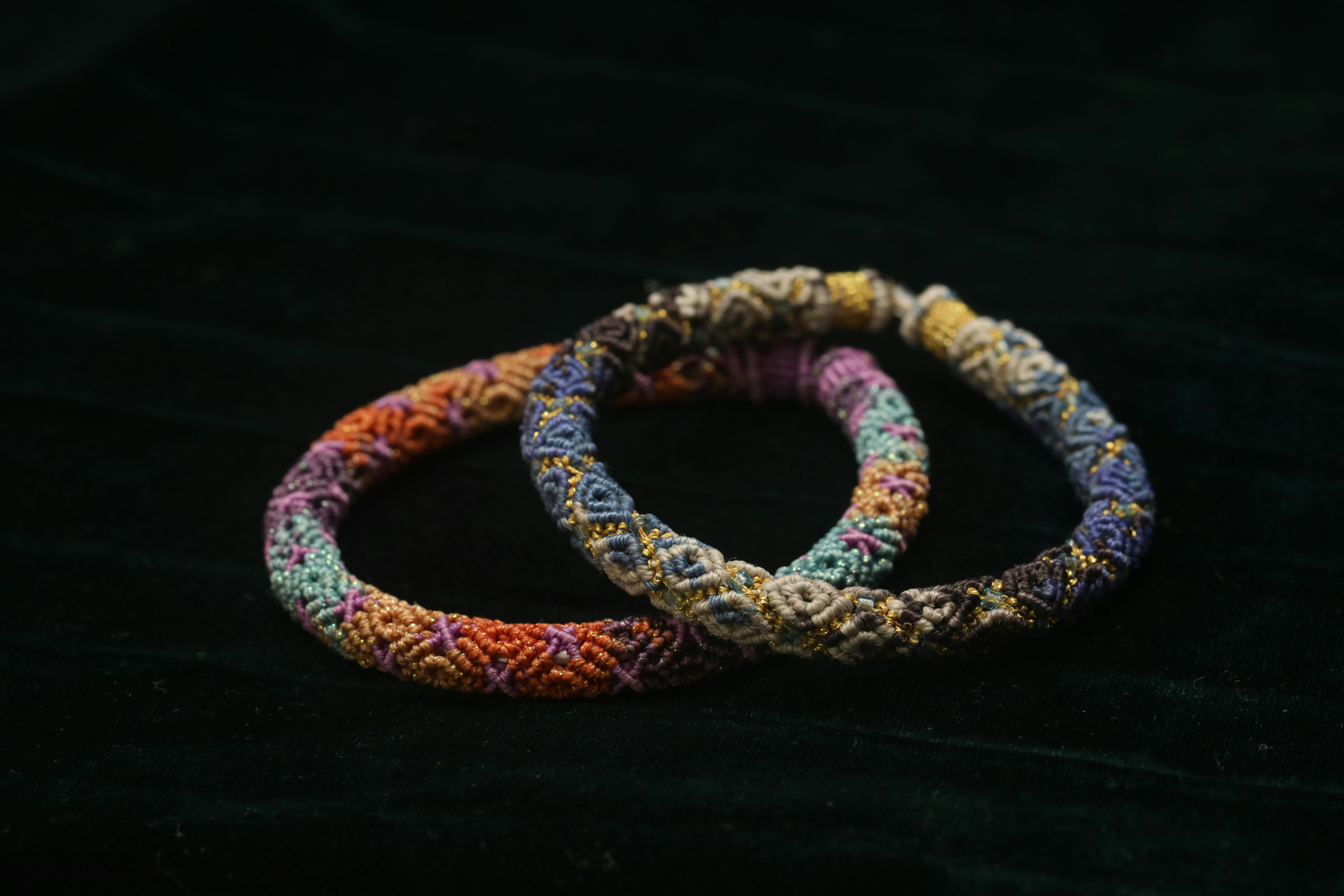 Two colorful woven bracelets on dark background