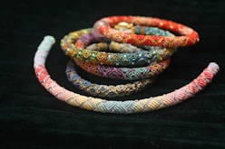 Colorful woven bracelets arranged on dark fabric.