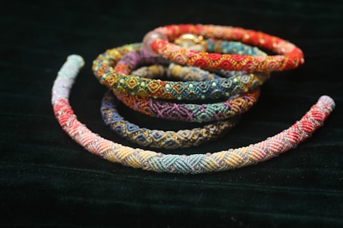 Colorful woven bracelets arranged on dark fabric.